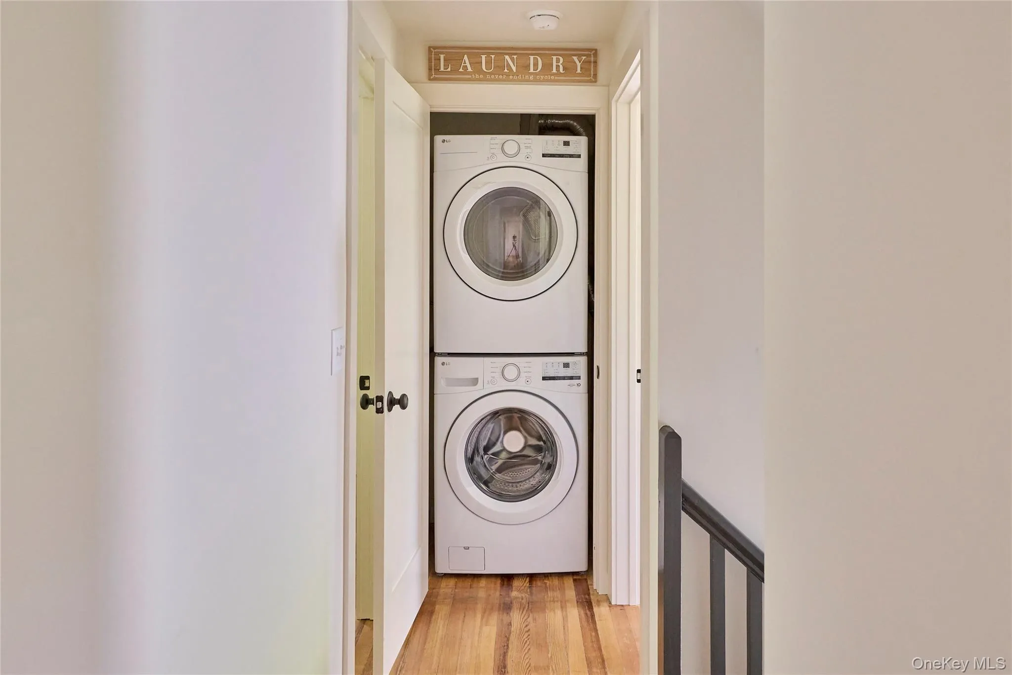 Laundry room with stacked washer and clothes dryer and light wood-style floors Laundry room with stacked washer and clothes dryer and light wood-style floors