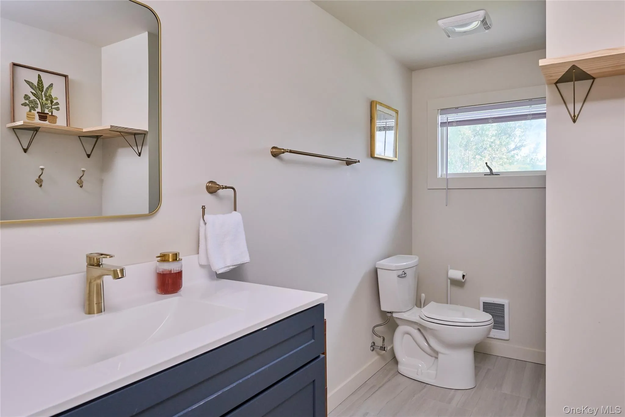 Bathroom featuring baseboards, vanity, toilet, and wood finished floors Bathroom featuring baseboards, vanity, toilet, and wood finished floors