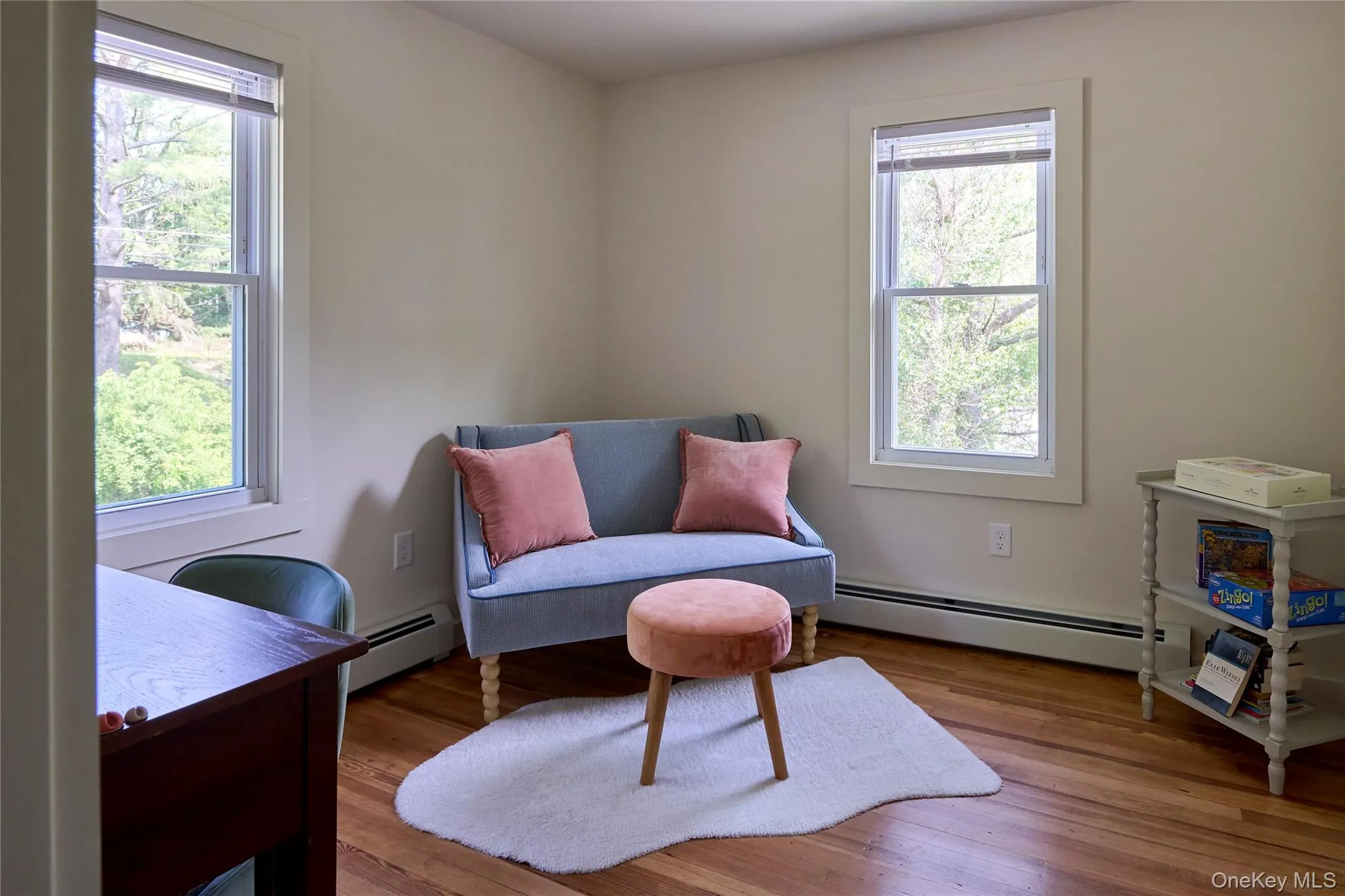 Sitting room featuring baseboard heating, healthy amount of natural light, and wood finished floors Sitting room featuring baseboard heating, healthy amount of natural light, and wood finished floors