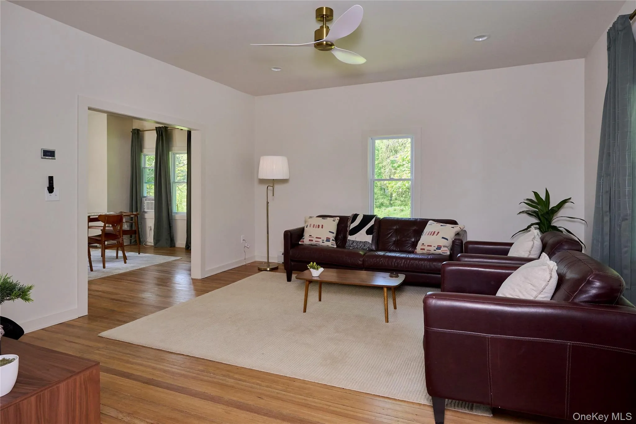Living room featuring plenty of natural light, a ceiling fan, wood finished floors, and baseboards Living room featuring plenty of natural light, a ceiling fan, wood finished floors, and baseboards