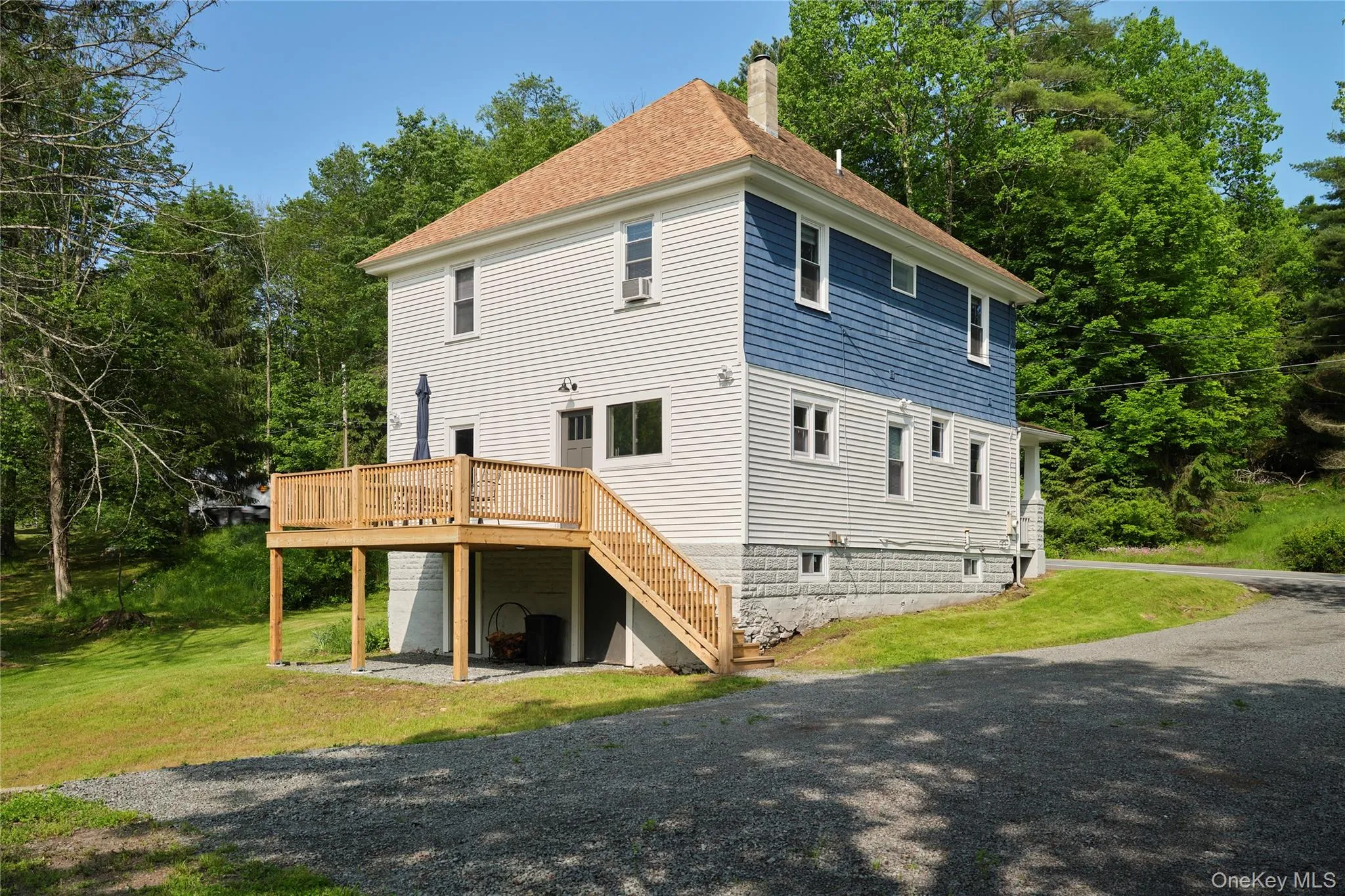 Rear view of house with a wooden deck, a lawn, a chimney, and stairs Rear view of house with a wooden deck, a lawn, a chimney, and stairs