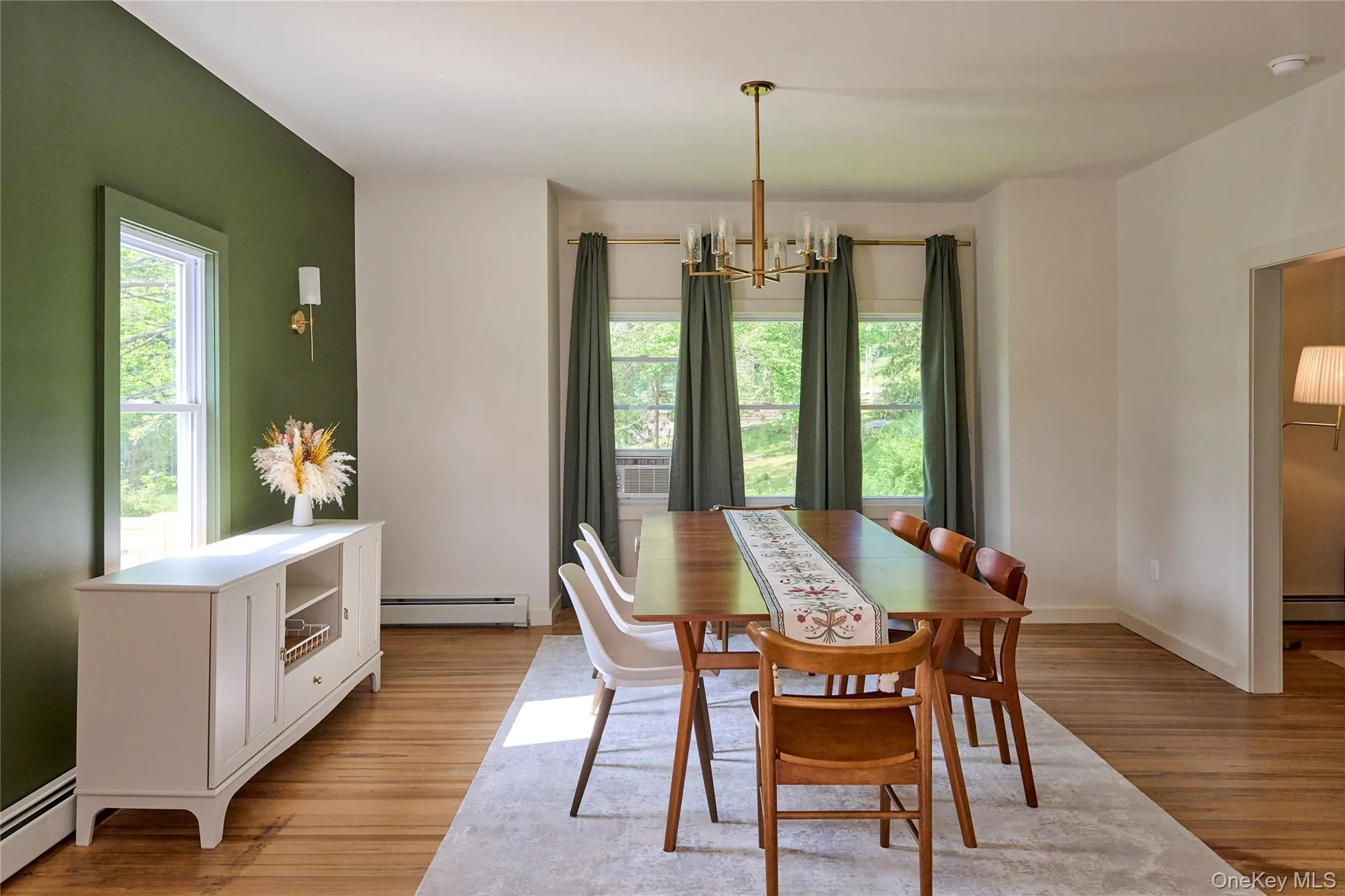 Dining room with a baseboard heating unit, a chandelier, light wood-type flooring, and baseboards Dining room with a baseboard heating unit, a chandelier, light wood-type flooring, and baseboards