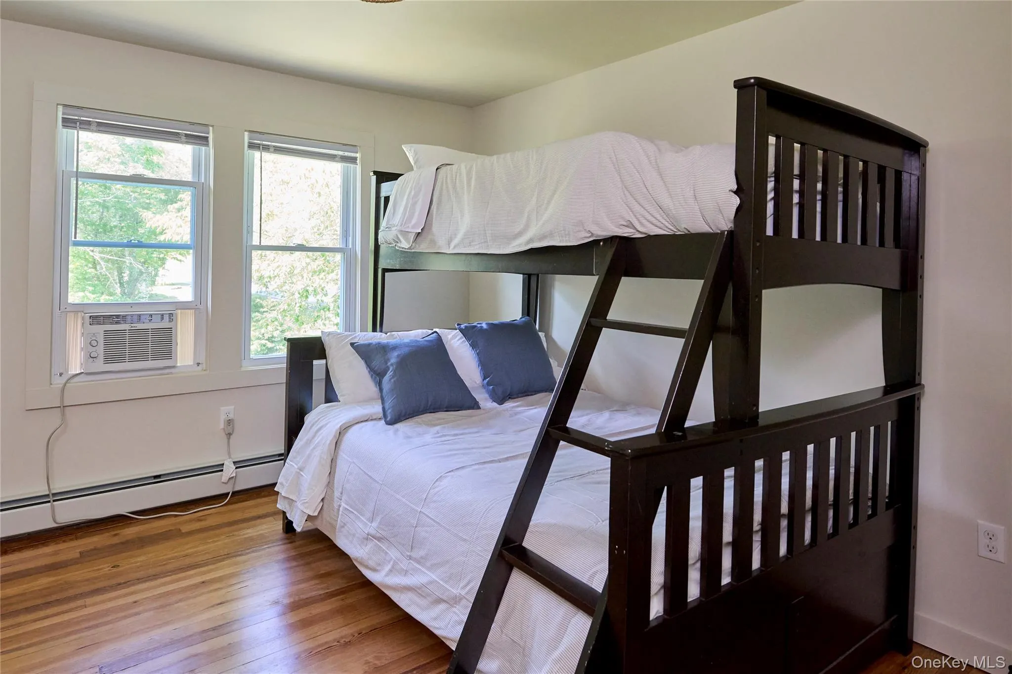 Bedroom with a baseboard heating unit, cooling unit, and wood finished floors Bedroom with a baseboard heating unit, cooling unit, and wood finished floors
