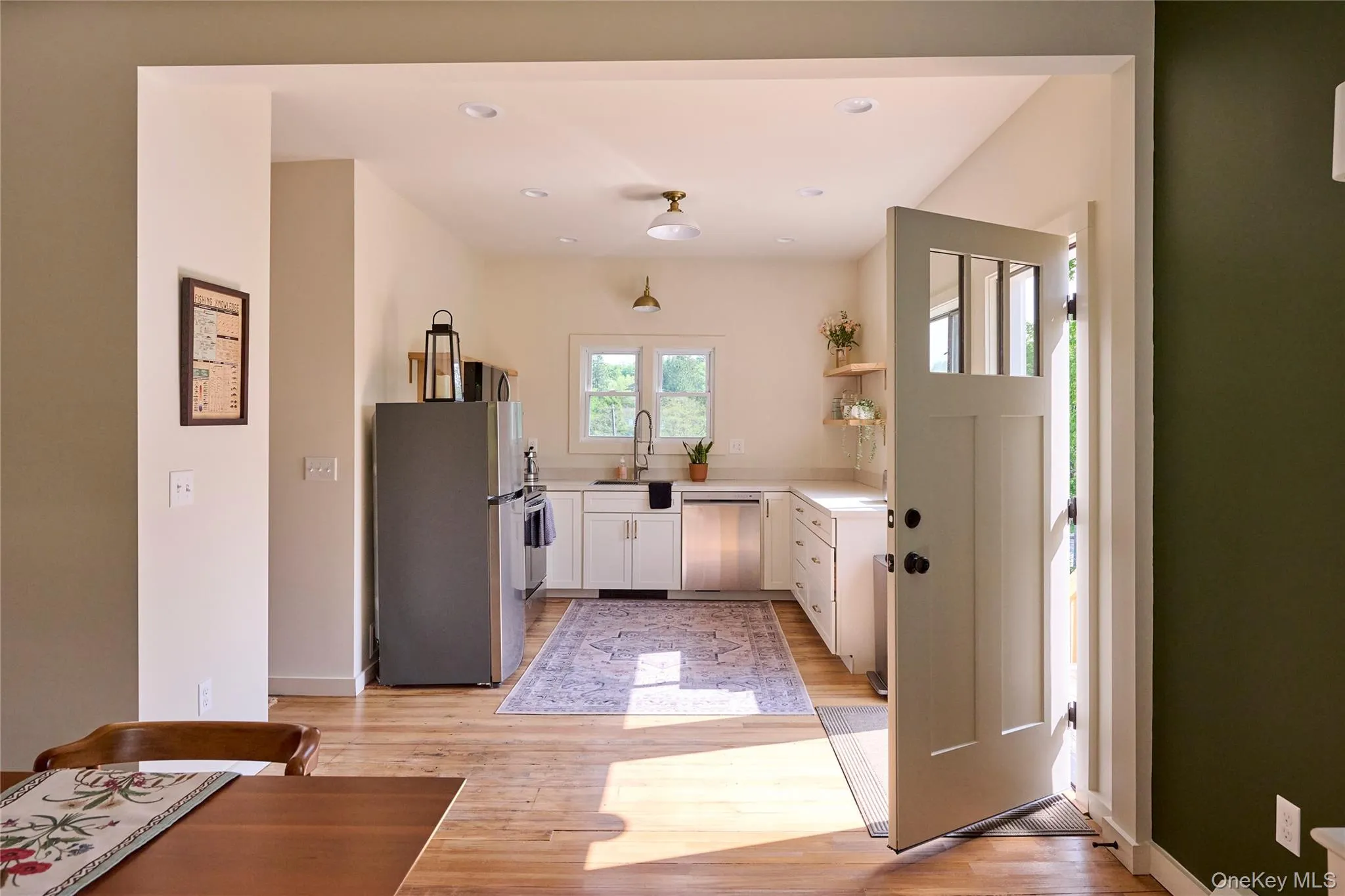 Kitchen with freestanding refrigerator, dishwashing machine, white cabinets, light wood finished floors, and recessed lighting Kitchen with freestanding refrigerator, dishwashing machine, white cabinets, light wood finished floors, and recessed lighting
