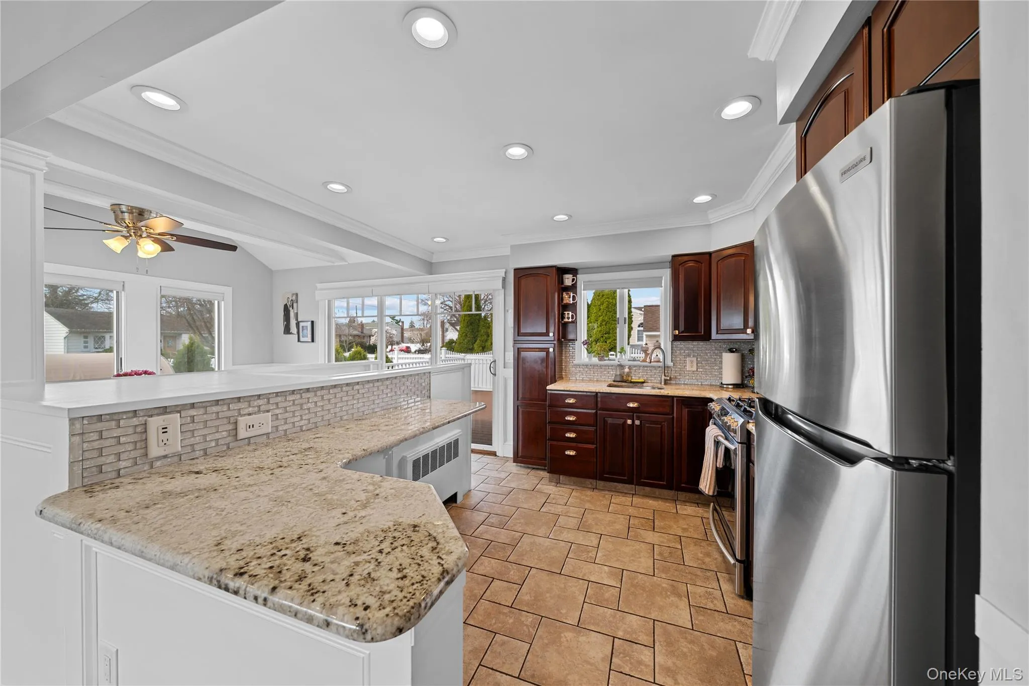 Kitchen featuring stainless steel appliances, decorative backsplash, light stone finish flooring, recessed lighting, and ornamental molding Kitchen featuring stainless steel appliances, decorative backsplash, light stone finish flooring, recessed lighting, and ornamental molding