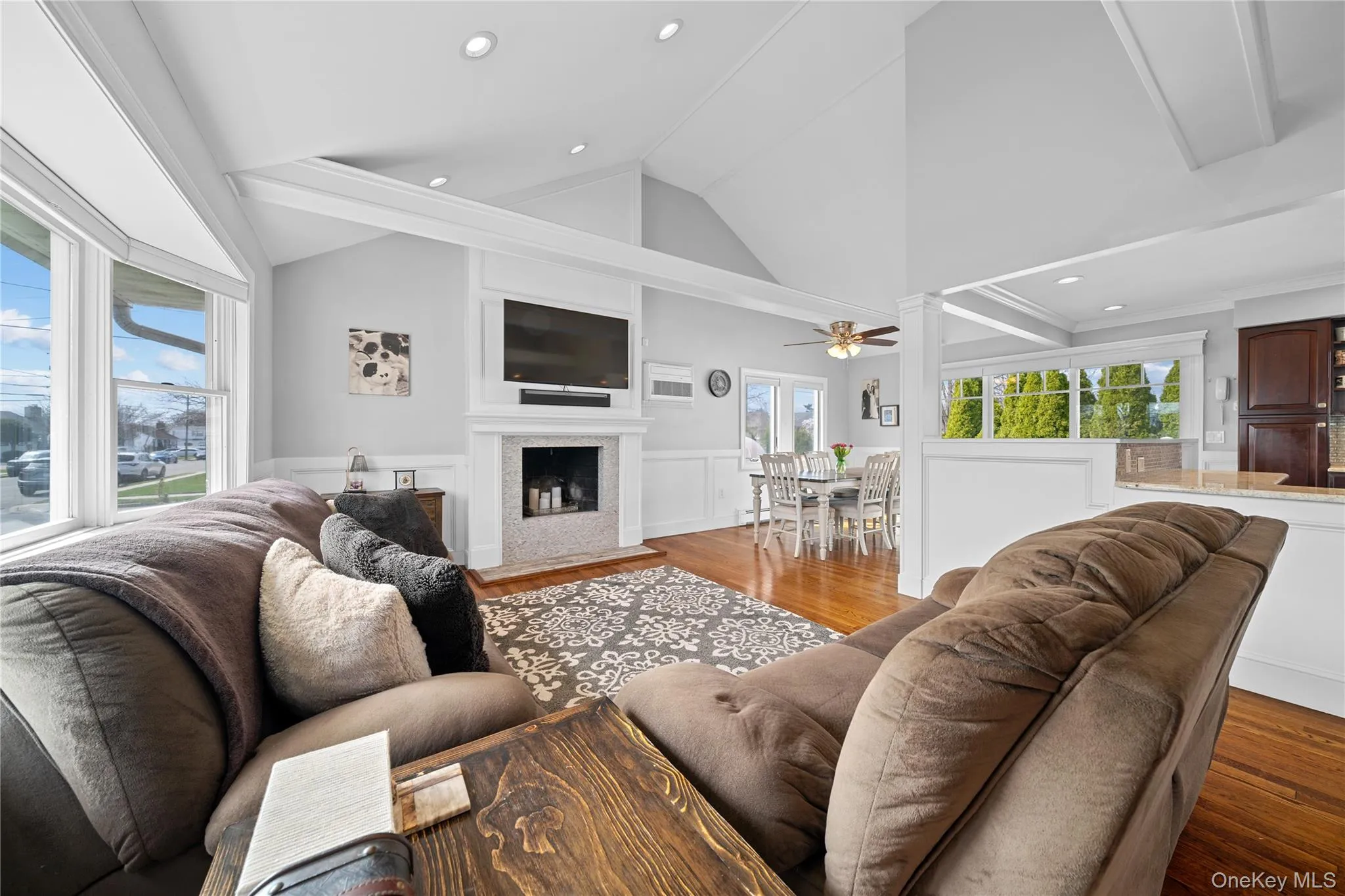 Living room with a wainscoted wall, wood finished floors, a decorative wall, lofted ceiling, and recessed lighting Living room with a wainscoted wall, wood finished floors, a decorative wall, lofted ceiling, and recessed lighting