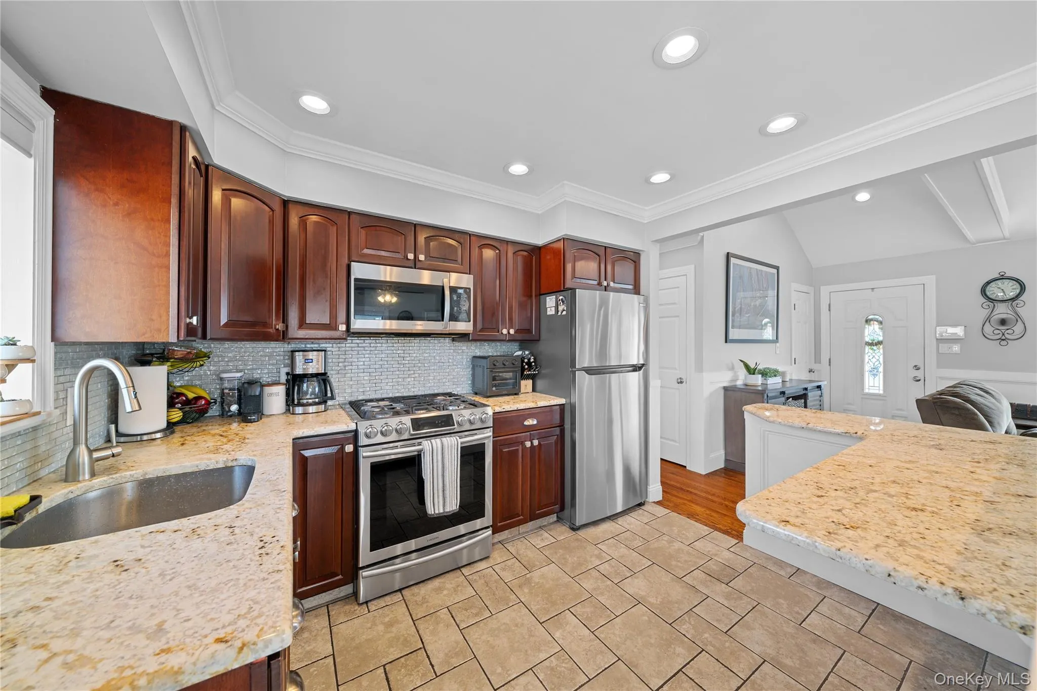 Kitchen featuring stainless steel appliances, light stone counters, recessed lighting, decorative backsplash, and dark wood finish cabinets Kitchen featuring stainless steel appliances, light stone counters, recessed lighting, decorative backsplash, and dark wood finish cabinets