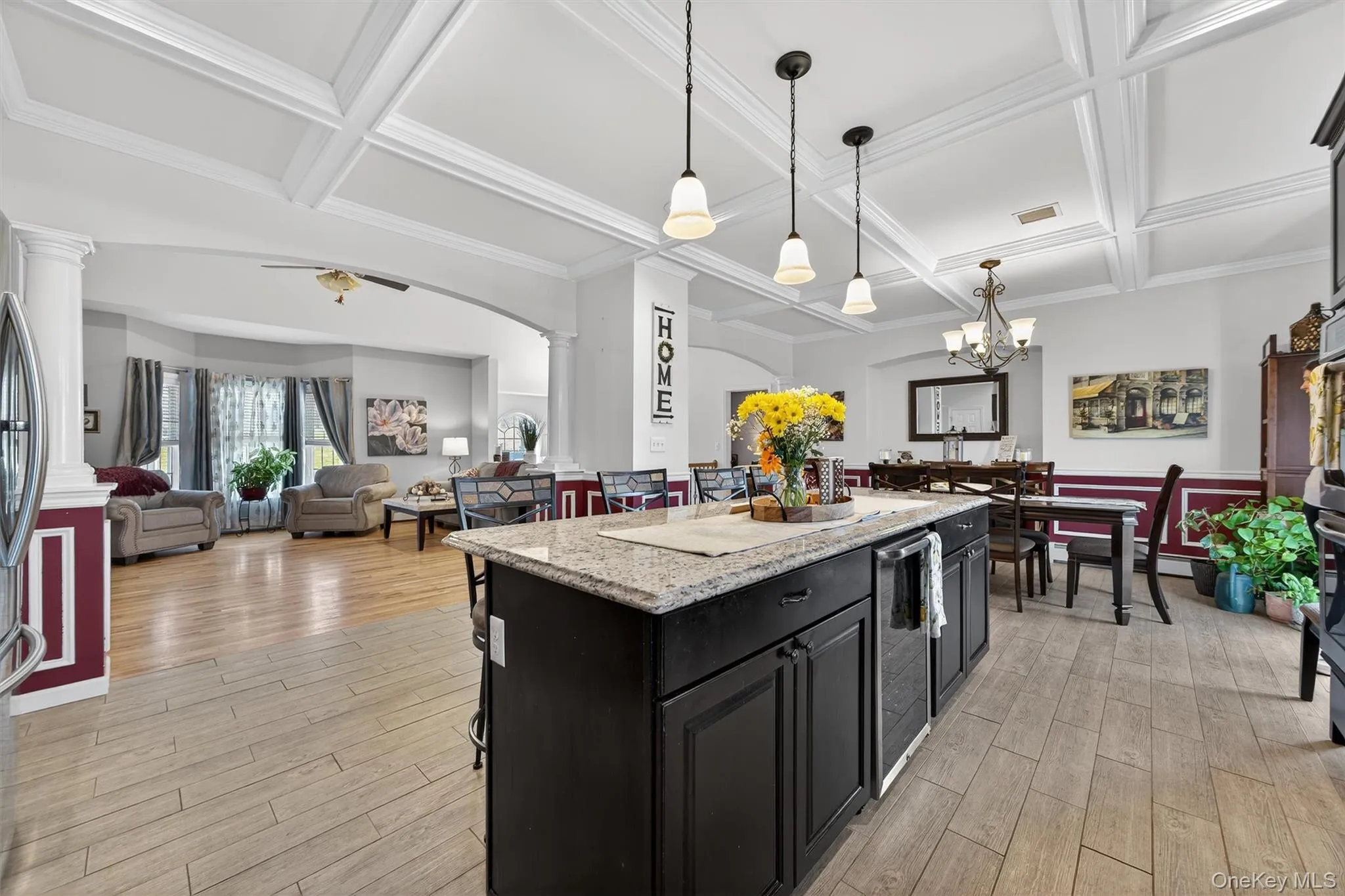 Kitchen with open floor plan, a breakfast bar, dark cabinetry, a center island, and coffered ceiling Kitchen with open floor plan, a breakfast bar, dark cabinetry, a center island, and coffered ceiling