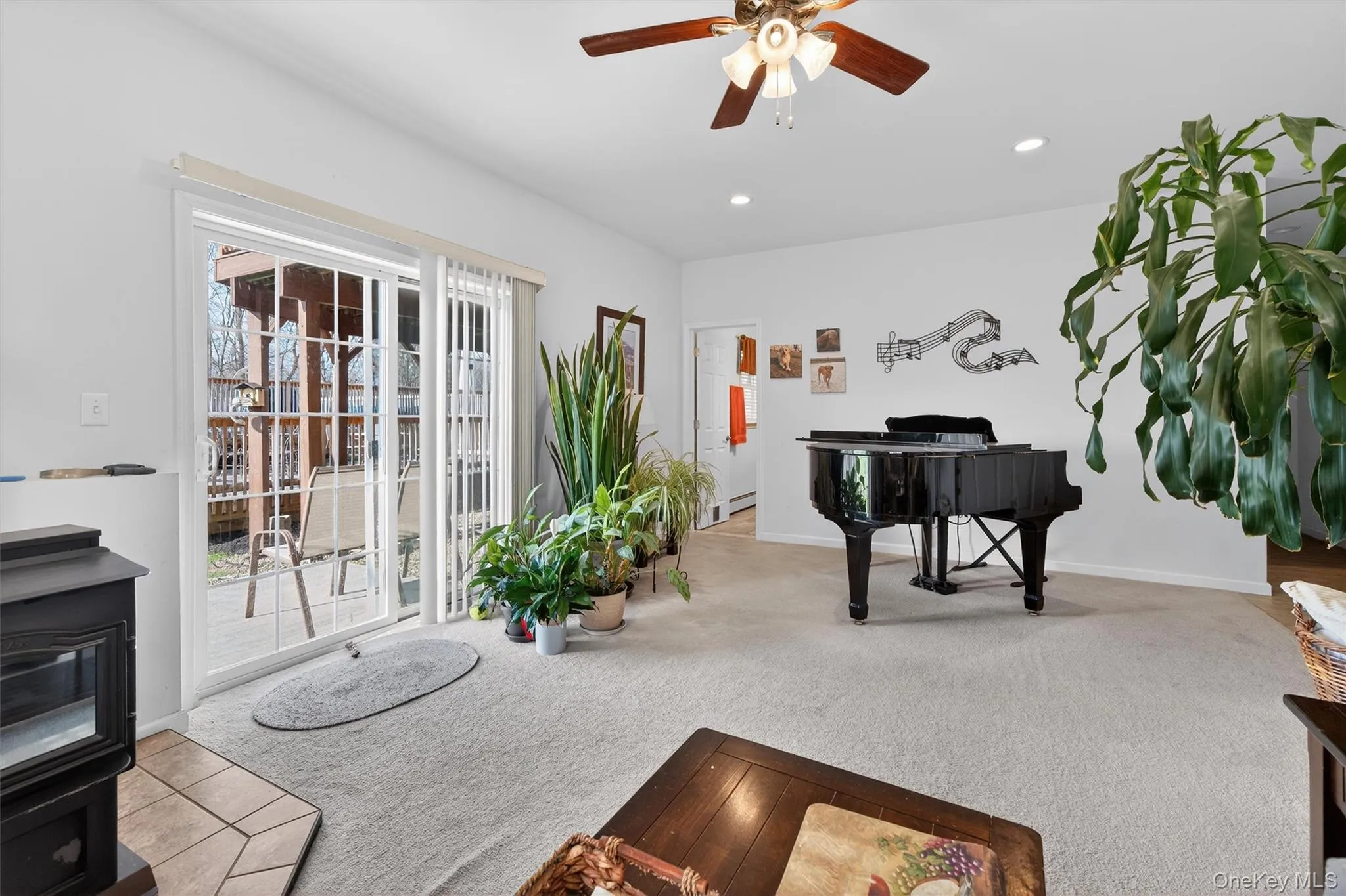 Living area with light colored carpet, a ceiling fan, a wood stove, and recessed lighting Living area with light colored carpet, a ceiling fan, a wood stove, and recessed lighting