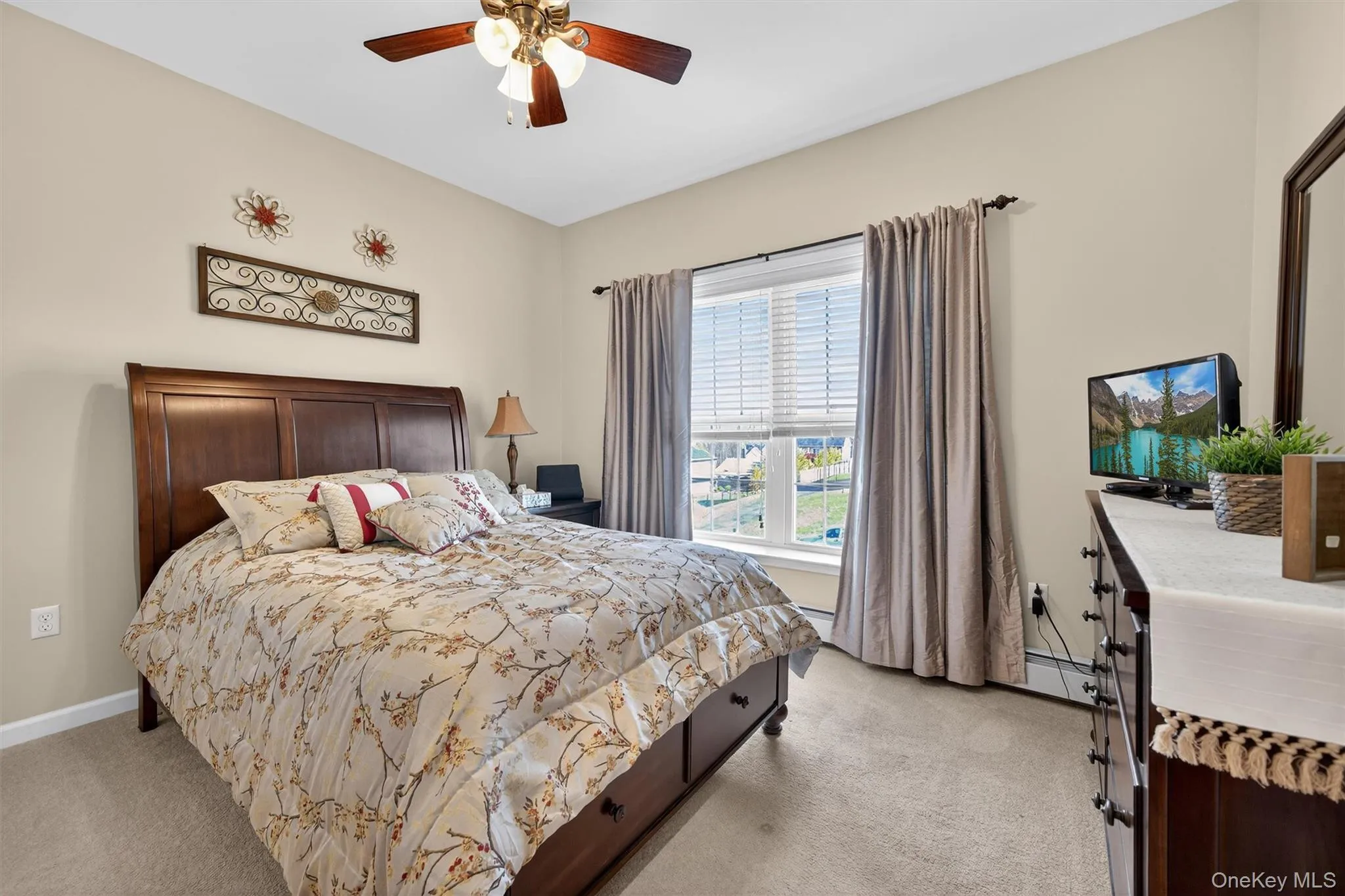 Bedroom featuring light colored carpet, ceiling fan, and a baseboard radiator Bedroom featuring light colored carpet, ceiling fan, and a baseboard radiator