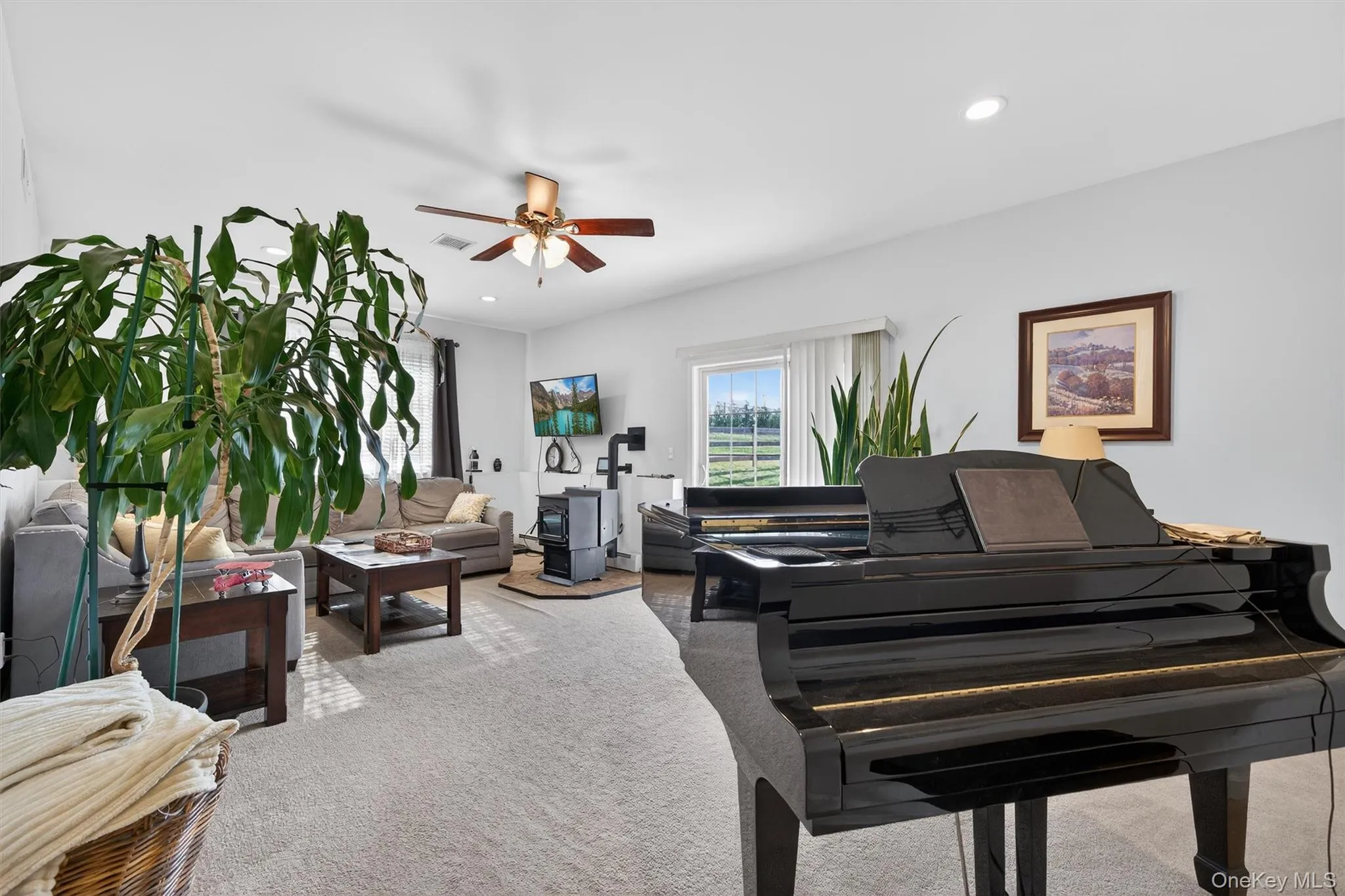 Living area with light colored carpet, a ceiling fan, a wood stove, and recessed lighting Living area with light colored carpet, a ceiling fan, a wood stove, and recessed lighting