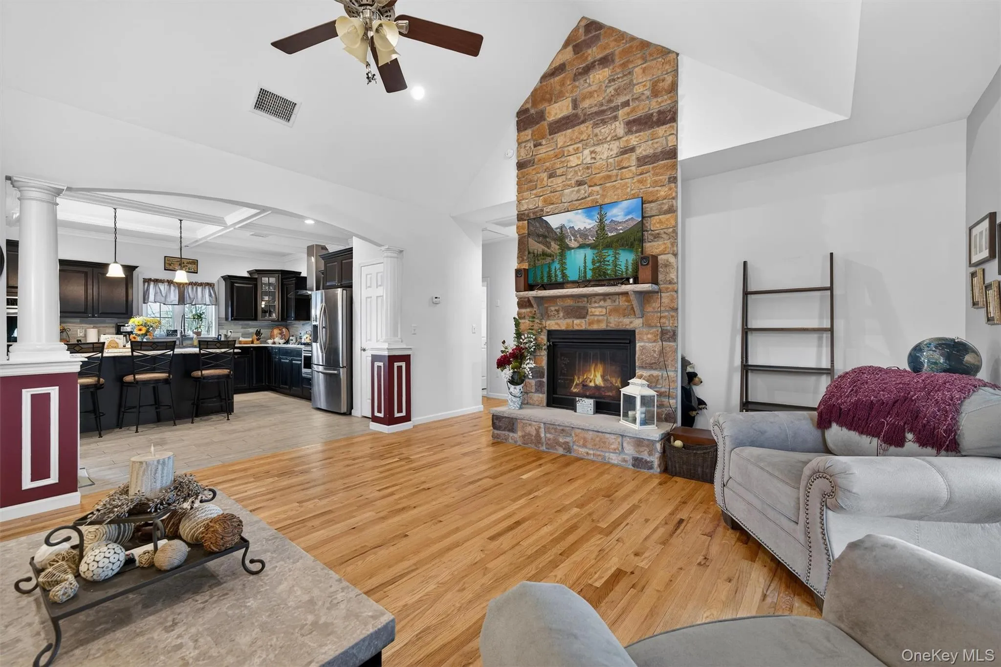 Living area with light wood-style floors, a stone fireplace, ceiling fan, recessed lighting, and lofted ceiling Living area with light wood-style floors, a stone fireplace, ceiling fan, recessed lighting, and lofted ceiling