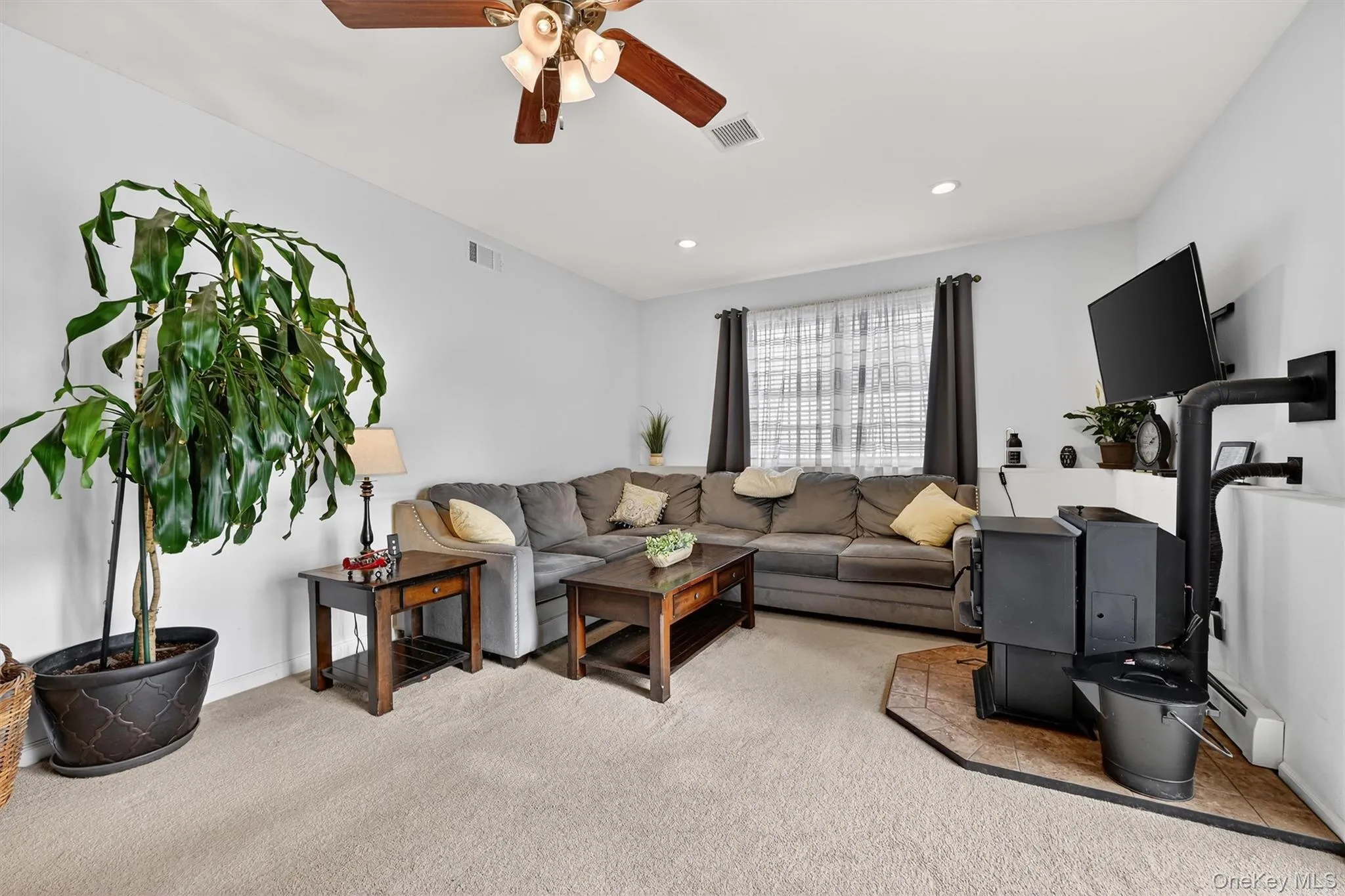 Living area with light carpet, ceiling fan, baseboard heating, and recessed lighting Living area with light carpet, ceiling fan, baseboard heating, and recessed lighting