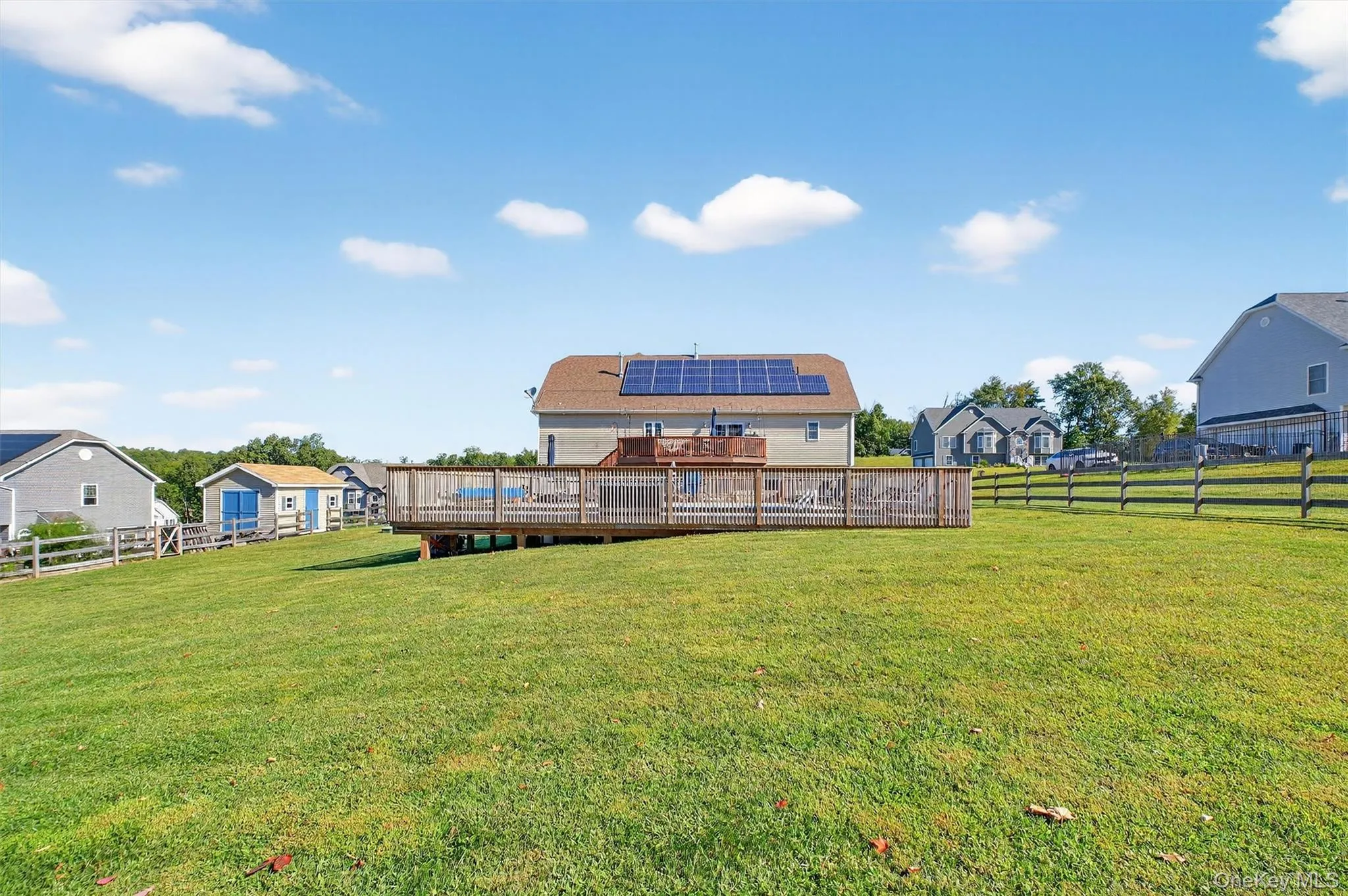 Back of property with solar panels, a residential view, and a wooden deck Back of property with solar panels, a residential view, and a wooden deck