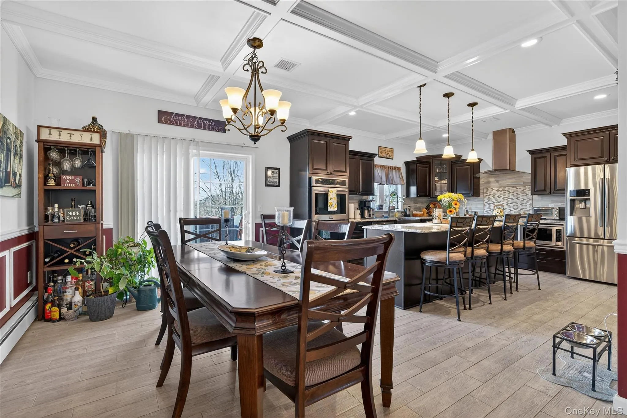 Dining room with hanging lights, coffered ceiling, light wood finished floors, a baseboard radiator, and wainscoting Dining room with hanging lights, coffered ceiling, light wood finished floors, a baseboard radiator, and wainscoting
