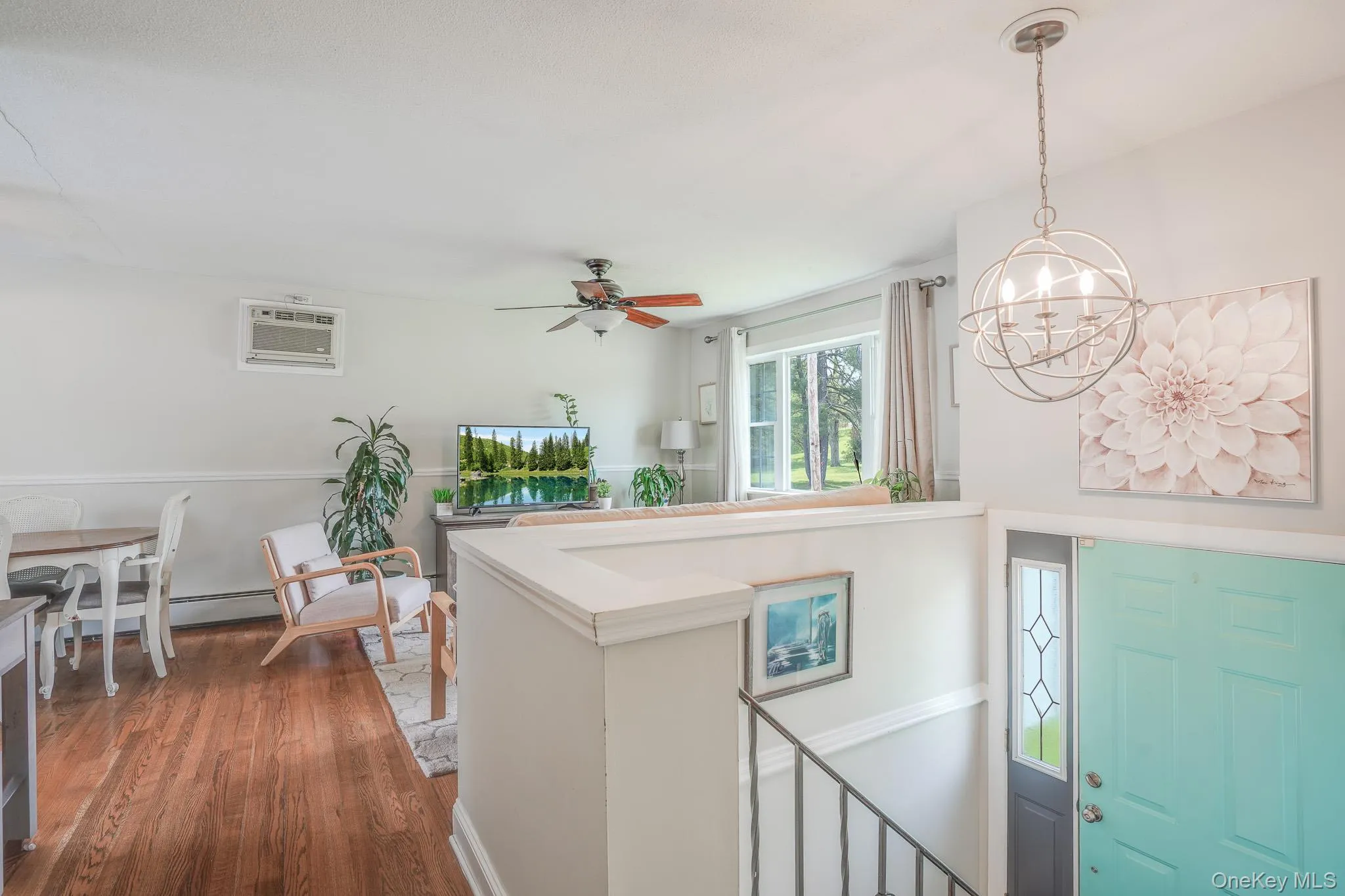 Entryway featuring a spherical chandelier, a teal front door with decorative glass, and a wrought iron railing Entryway featuring a spherical chandelier, a teal front door with decorative glass, and a wrought iron railing