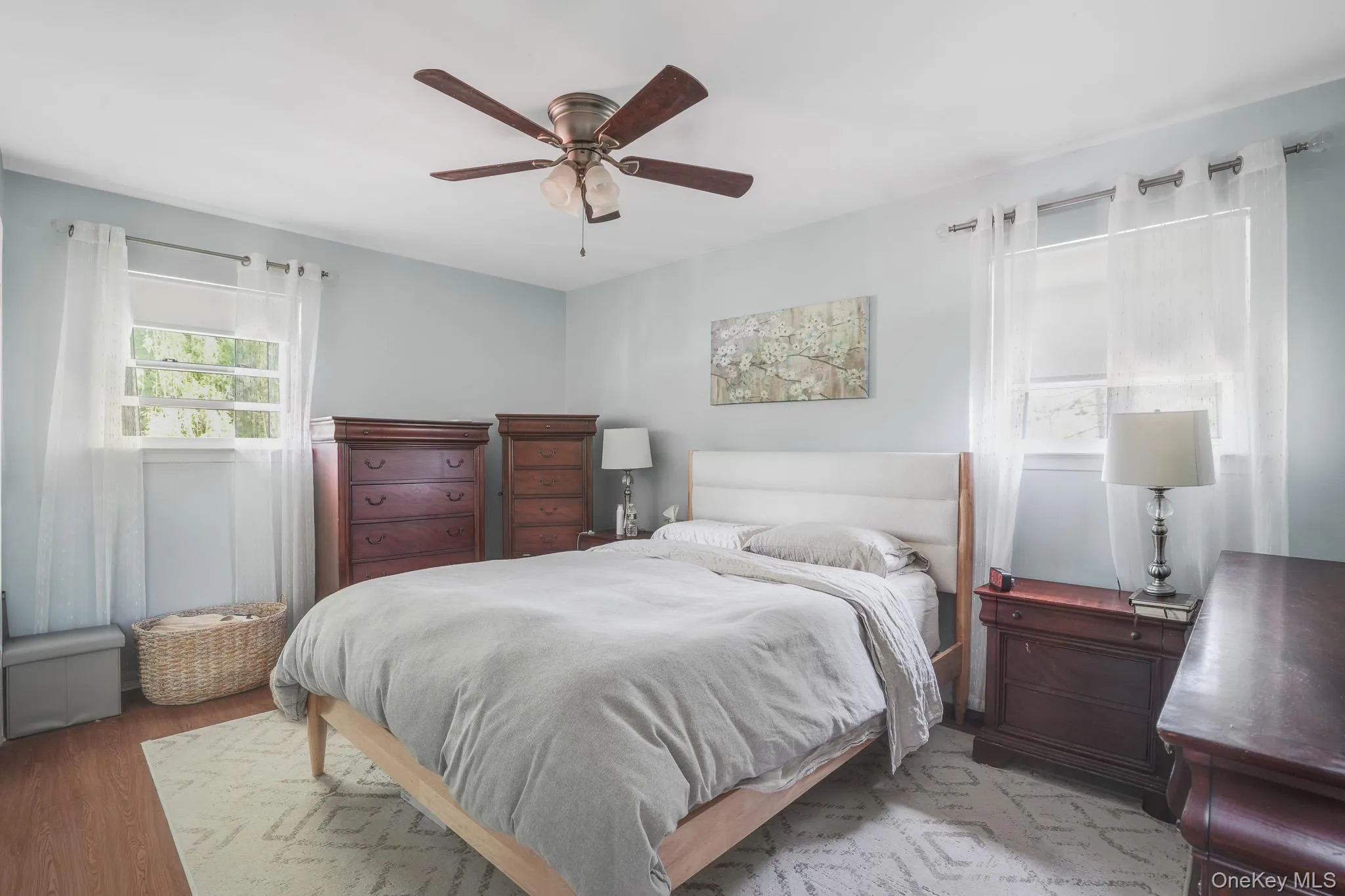Room featuring wood-finish flooring, light blue wall tones, and a ceiling fan with integrated lighting Room featuring wood-finish flooring, light blue wall tones, and a ceiling fan with integrated lighting