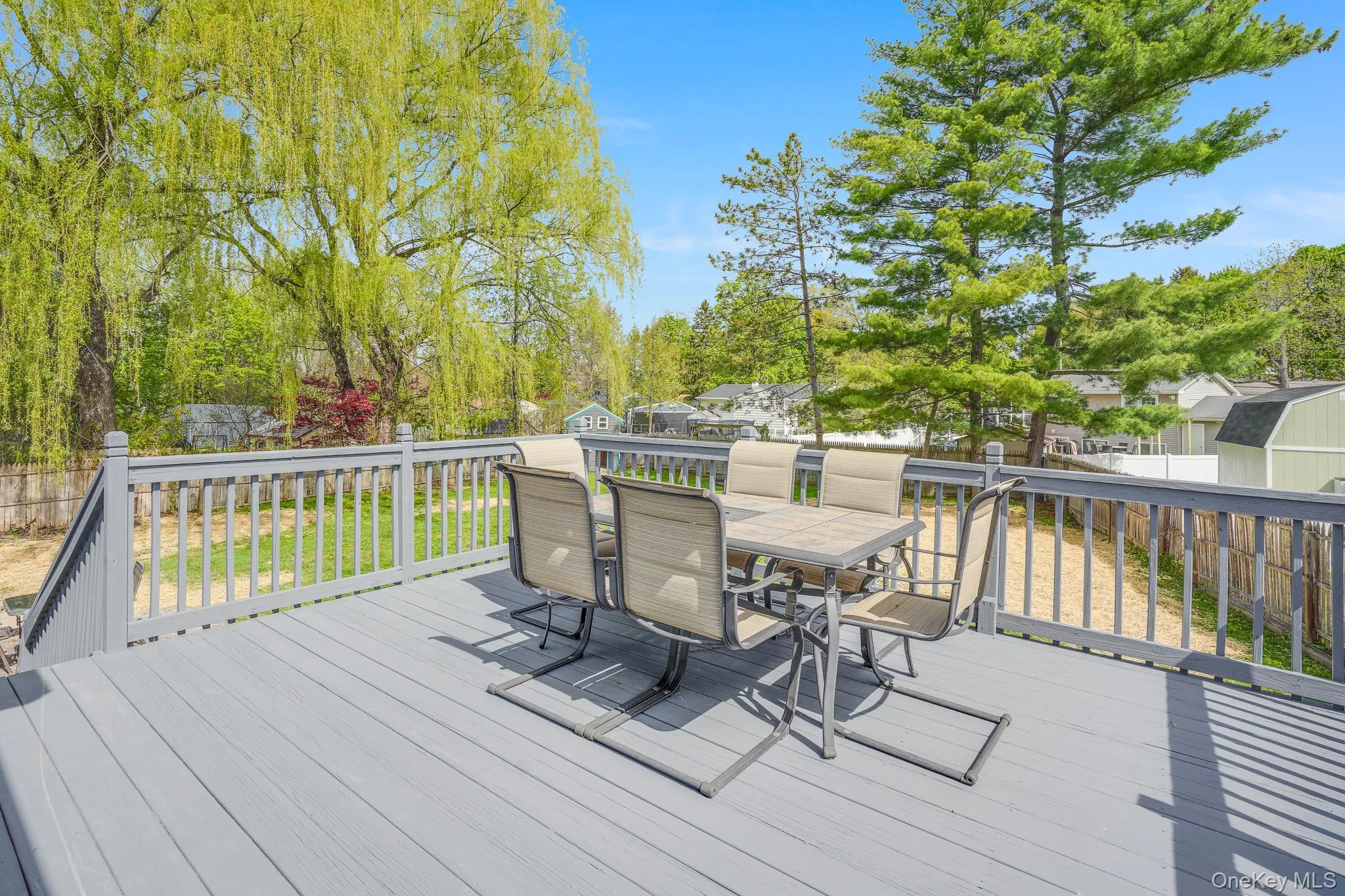 Expansive gray wood-finish deck featuring a full railing system and stairs Expansive gray wood-finish deck featuring a full railing system and stairs