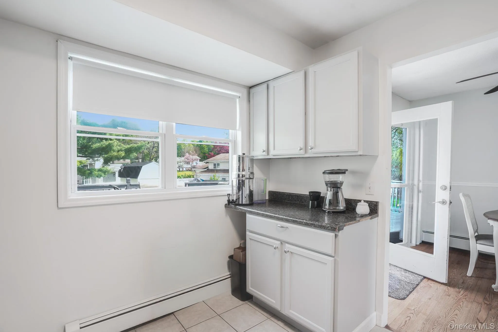 White cabinetry with dark countertop and tile flooring White cabinetry with dark countertop and tile flooring
