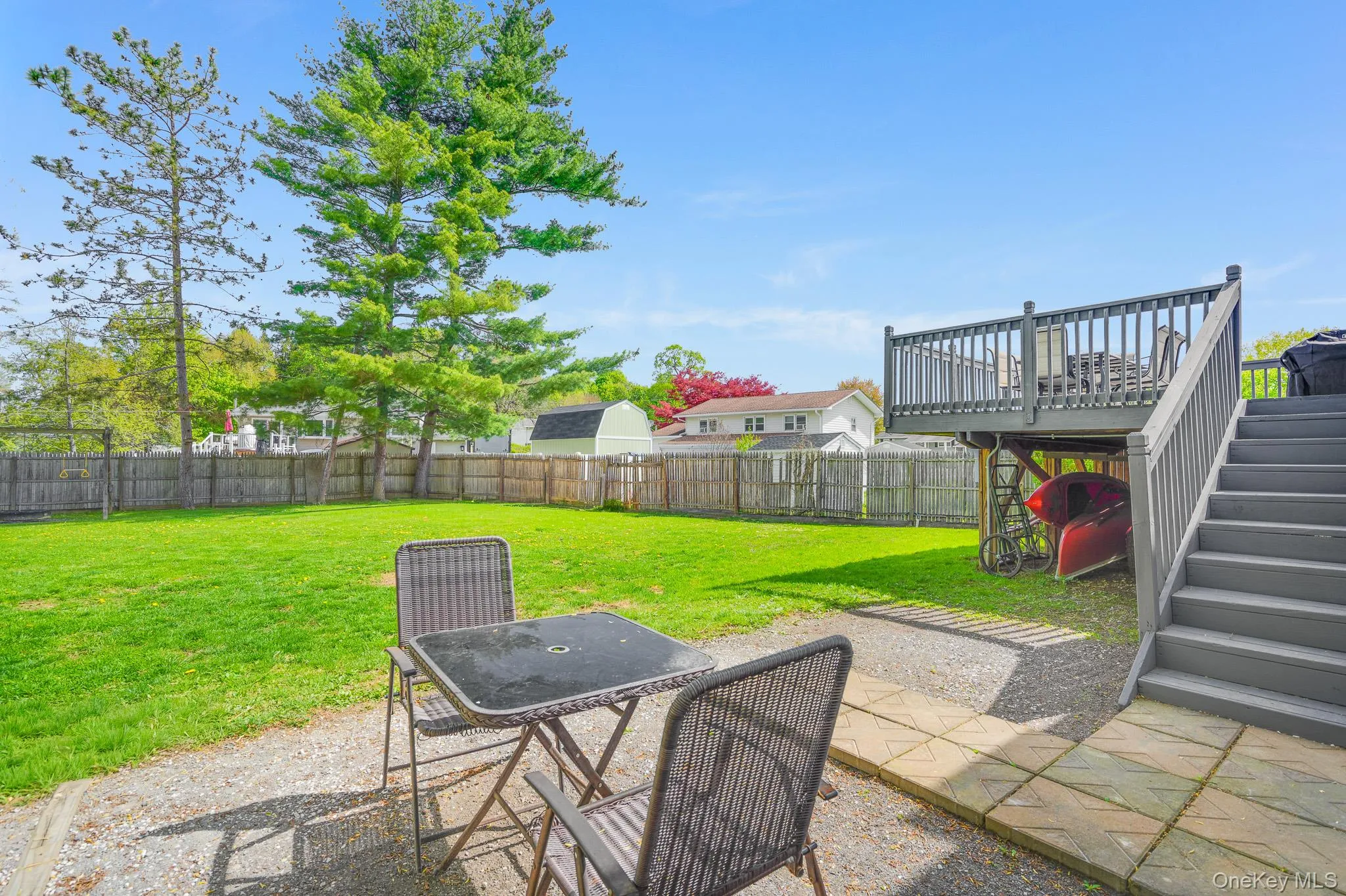 Spacious backyard featuring a multi-level deck with stairs, a large grassy area, mature trees, and a wooden fence Spacious backyard featuring a multi-level deck with stairs, a large grassy area, mature trees, and a wooden fence