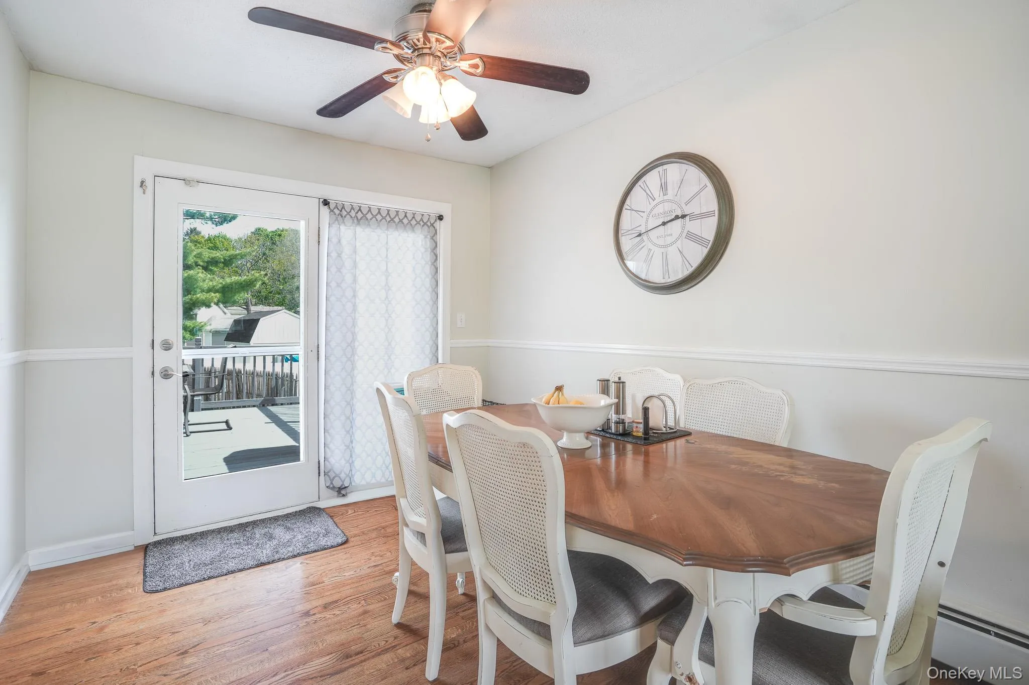 Dining area featuring wood-finish flooring, a ceiling fan with integrated lighting, and chair rail molding Dining area featuring wood-finish flooring, a ceiling fan with integrated lighting, and chair rail molding