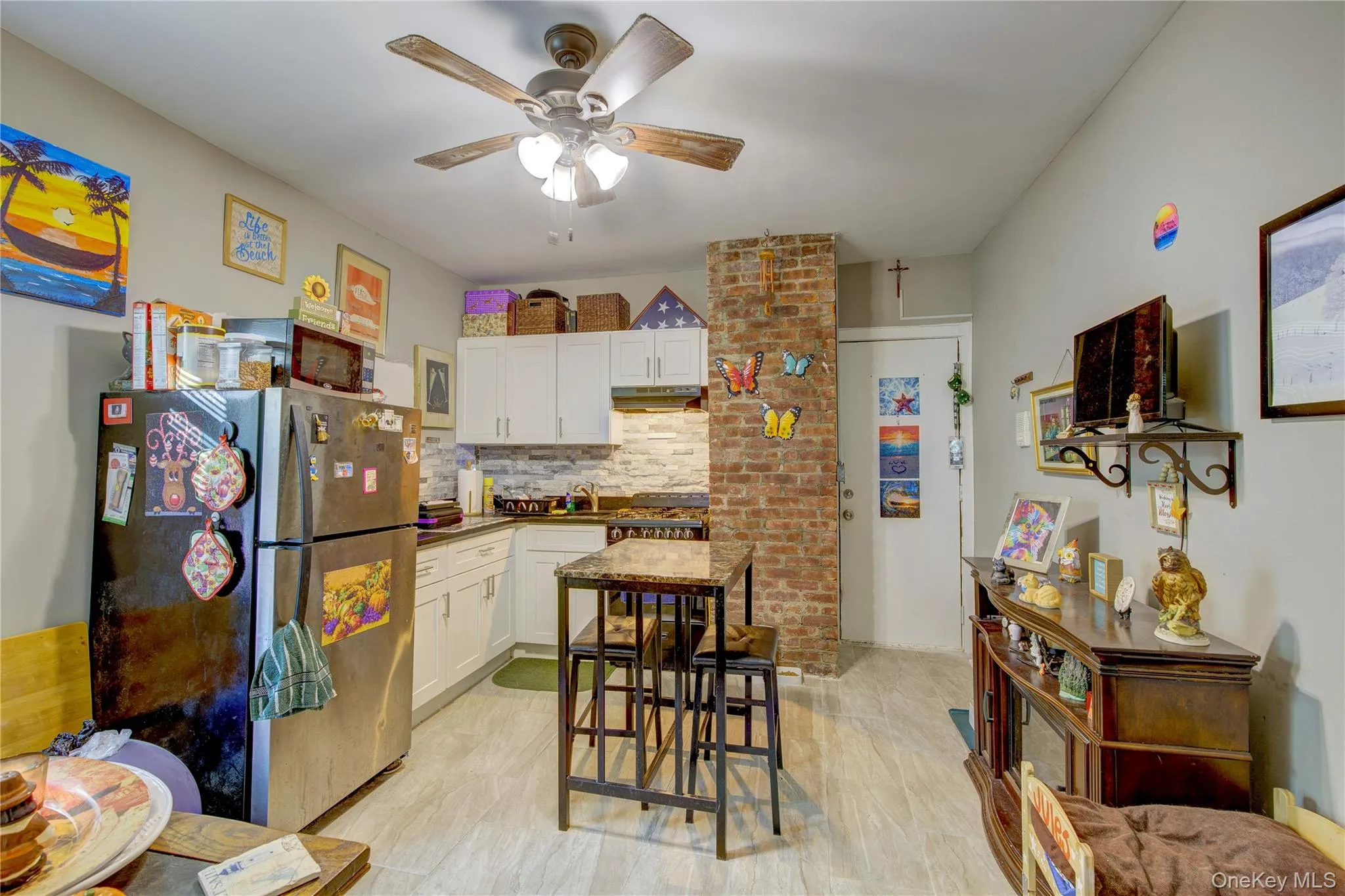 Kitchen featuring white cabinets, ceiling fan, backsplash, and stainless steel refrigerator Kitchen featuring white cabinets, ceiling fan, backsplash, and stainless steel refrigerator