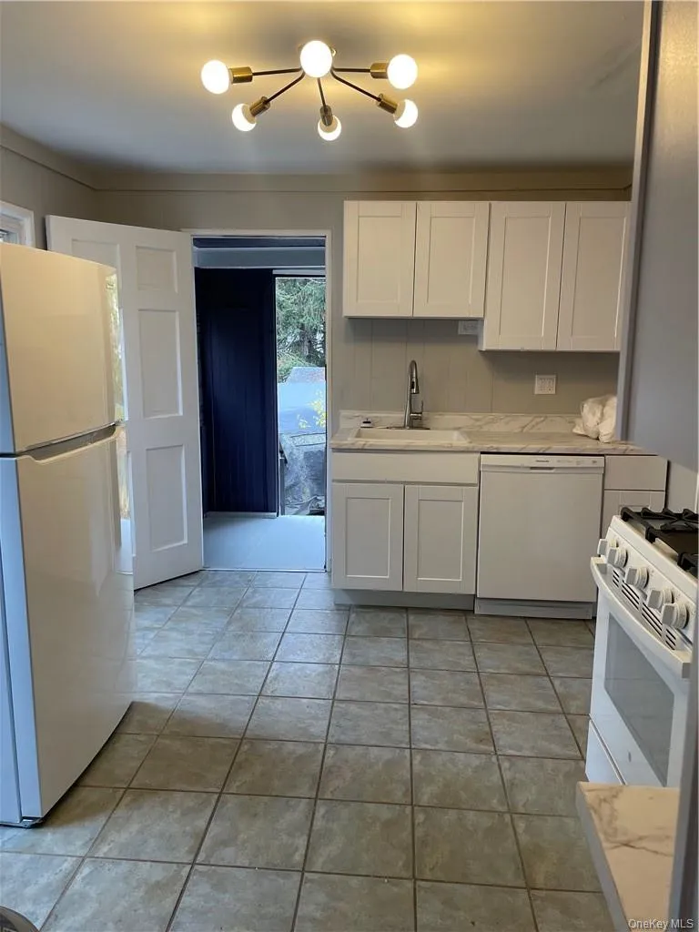 Kitchen with white cabinetry, dishwasher range, sink, and refrigerator. Rear mudroom for storage and rear yard access. Kitchen with white cabinetry, dishwasher range, sink, and refrigerator. Rear mudroom for storage and rear yard access.