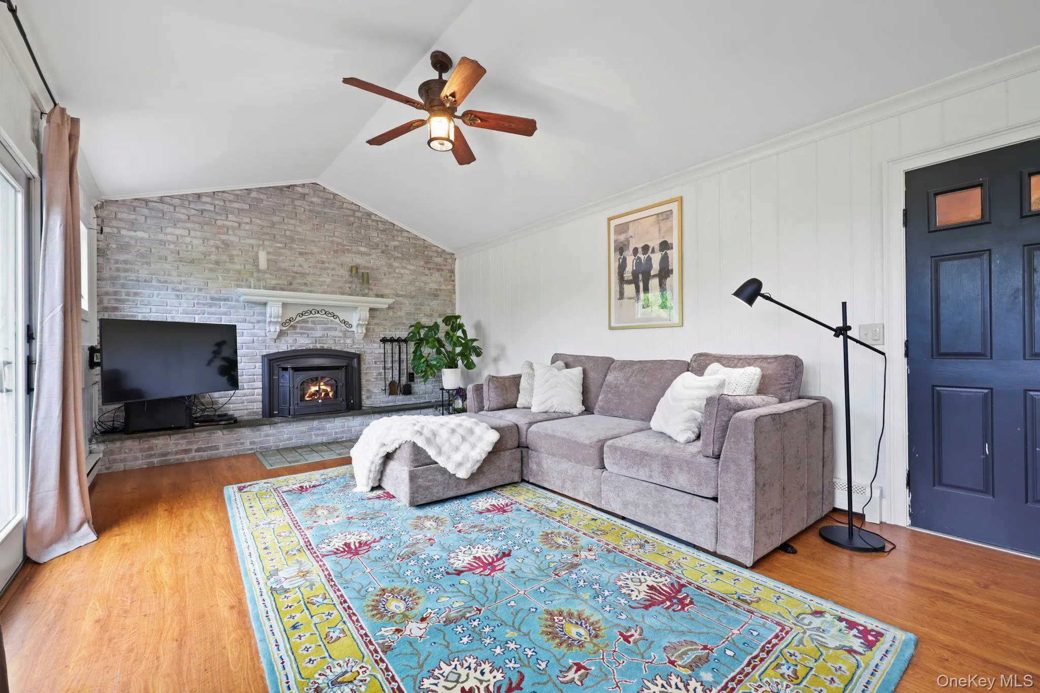 Family room with access to second deck , vaulted ceilings and fireplace insert against stone clad accent wall Family room with access to second deck , vaulted ceilings and fireplace insert against stone clad accent wall