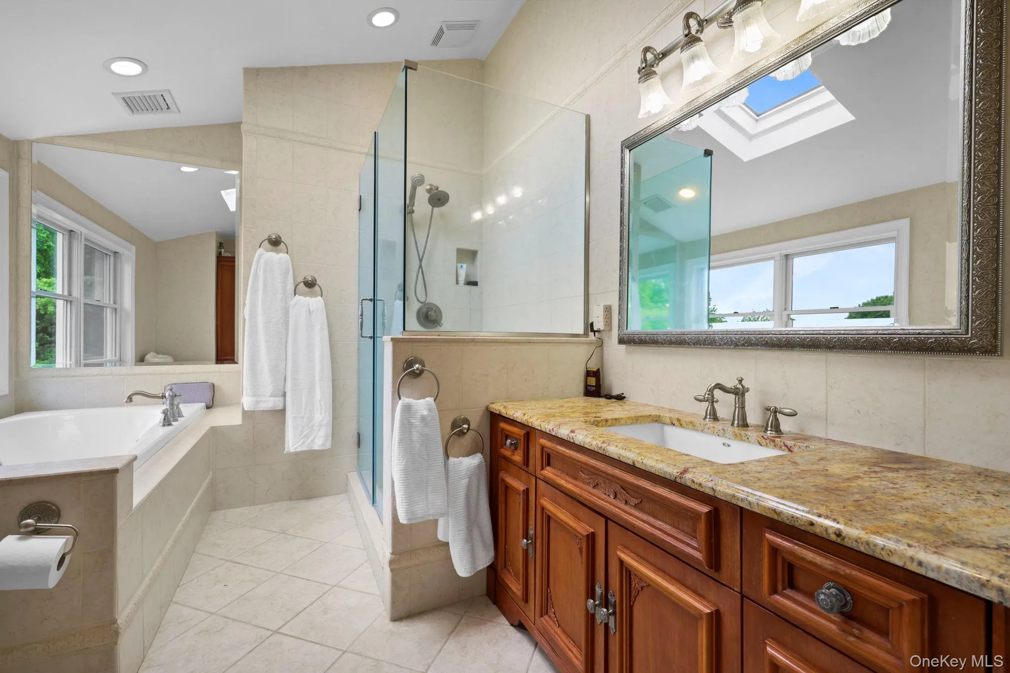 Spa like bathroom with soaking tub looking out on backyard with mature landscaping Spa like bathroom with soaking tub looking out on backyard with mature landscaping