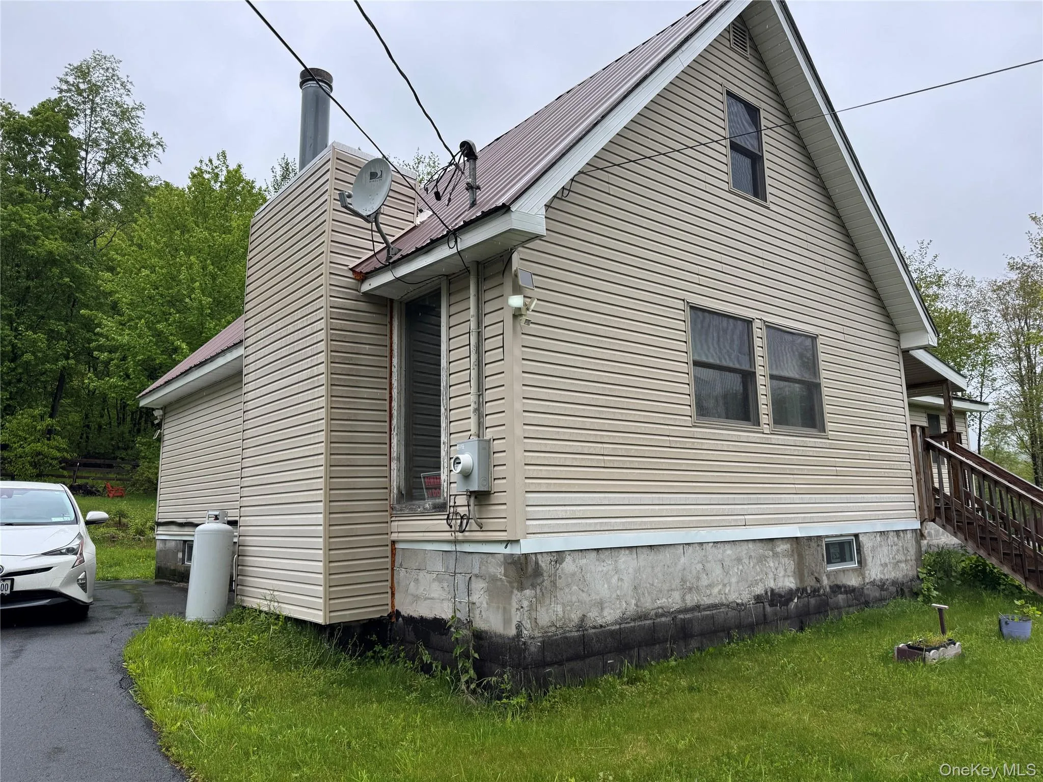 View of property exterior featuring a chimney, stairs, metal roof, and a lawn View of property exterior featuring a chimney, stairs, metal roof, and a lawn