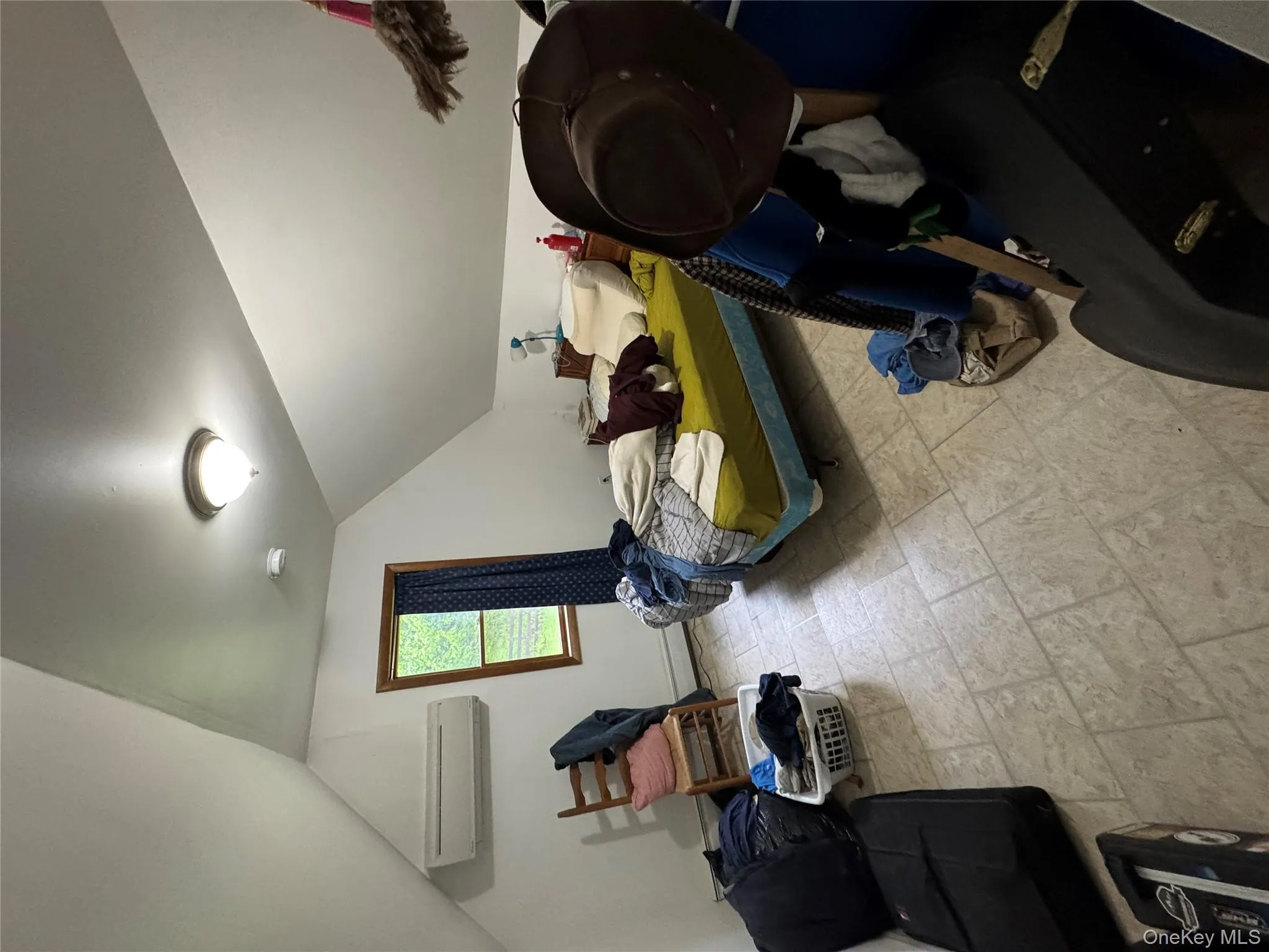 Bedroom featuring an AC wall unit, stone finish floors, vaulted ceiling, and a baseboard heating unit Bedroom featuring an AC wall unit, stone finish floors, vaulted ceiling, and a baseboard heating unit