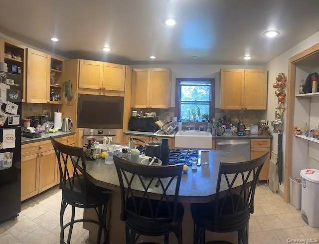 Kitchen featuring open shelves, freestanding refrigerator, a sink, a breakfast bar area, and recessed lighting Kitchen featuring open shelves, freestanding refrigerator, a sink, a breakfast bar area, and recessed lighting