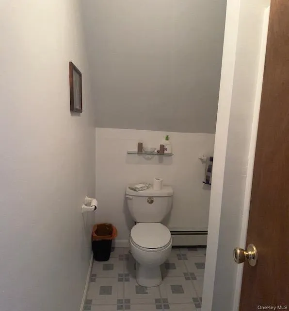 Bathroom featuring baseboard heating, toilet, and baseboards Bathroom featuring baseboard heating, toilet, and baseboards