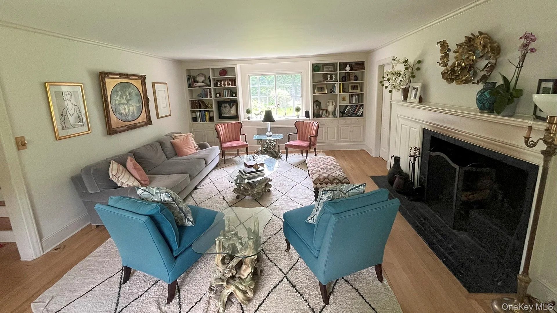 Living room featuring wood finished floors, built in shelves, ornamental molding, and a fireplace with flush hearth Living room featuring wood finished floors, built in shelves, ornamental molding, and a fireplace with flush hearth