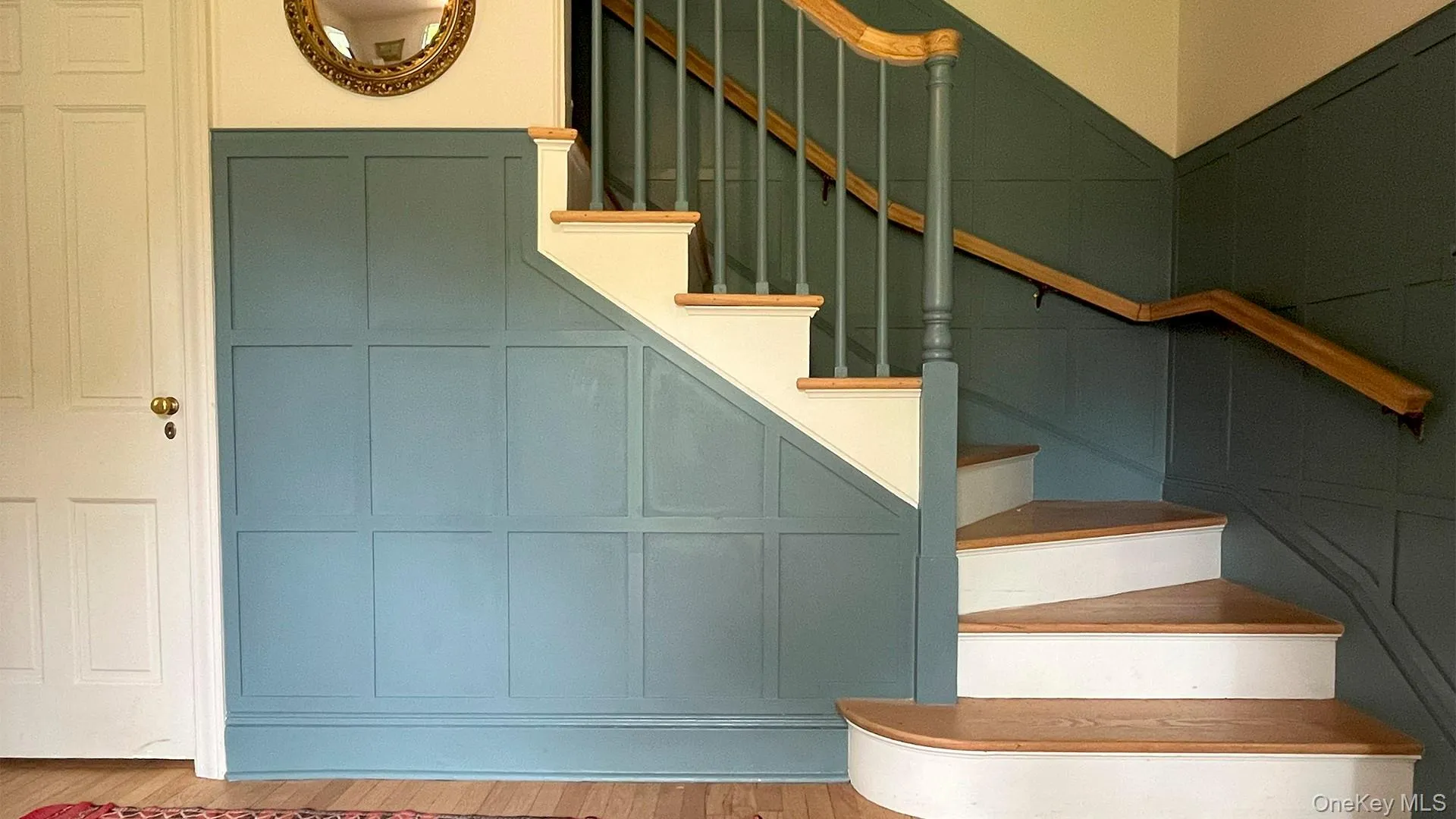 Stairs featuring a decorative wall and wood finished floors Stairs featuring a decorative wall and wood finished floors