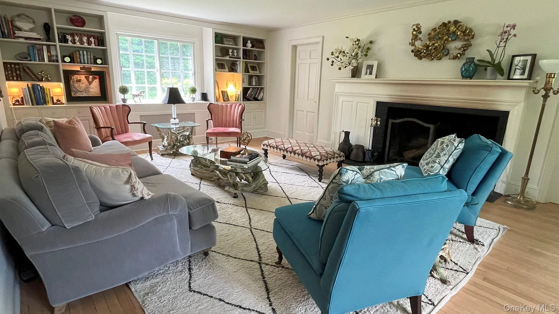 Living room featuring wood finished floors, a fireplace, and built in shelves Living room featuring wood finished floors, a fireplace, and built in shelves