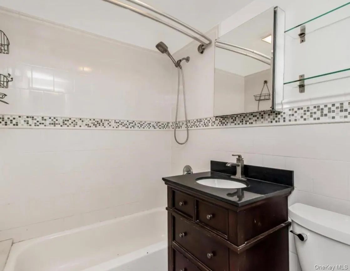 Full bathroom featuring shower / washtub combination, vanity, and tile walls Full bathroom featuring shower / washtub combination, vanity, and tile walls
