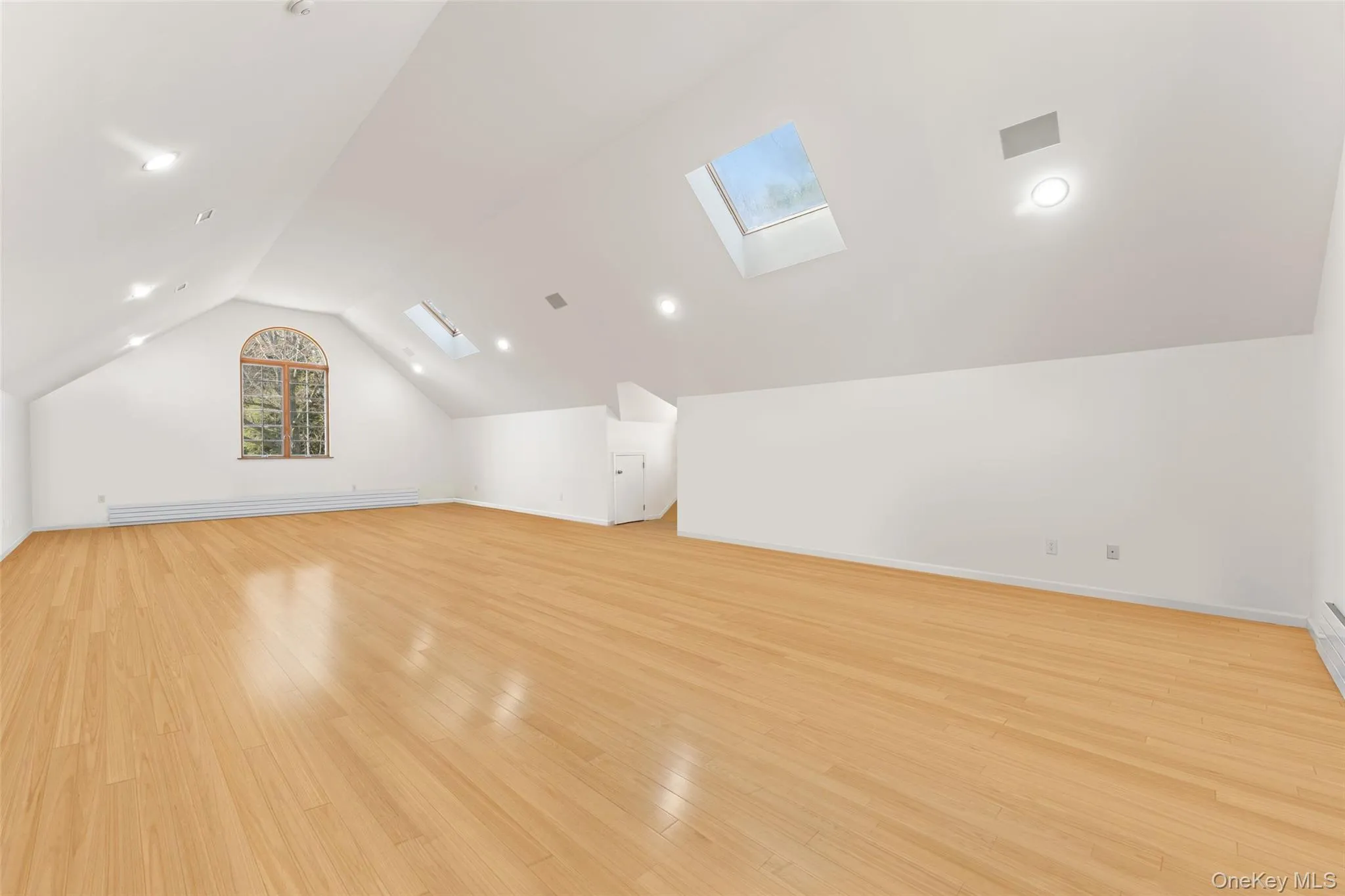 2nd floor recreation room featuring a skylight, light wood-style floors, and baseboard heating 2nd floor recreation room featuring a skylight, light wood-style floors, and baseboard heating