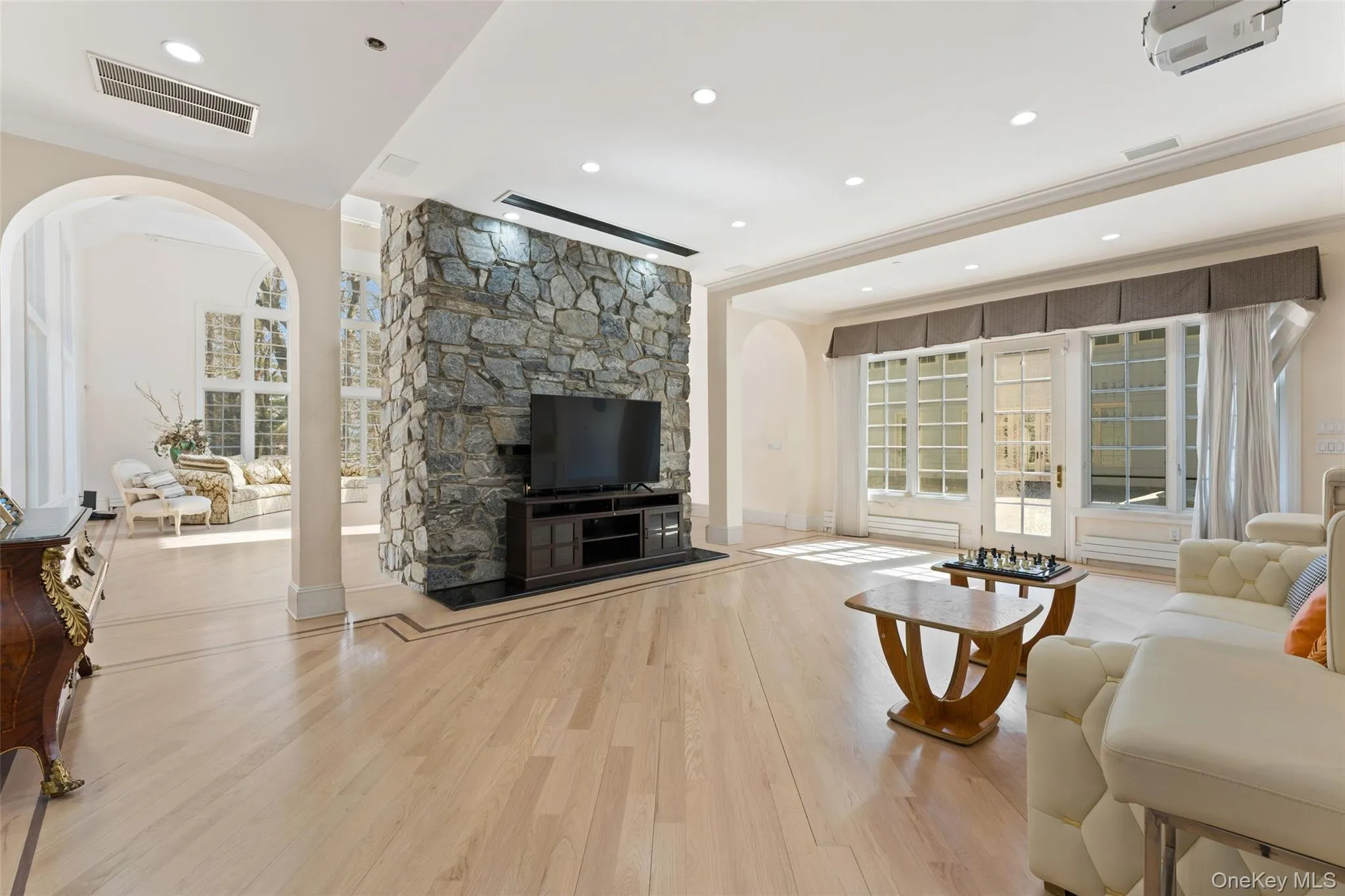 Living area featuring arched walkways, light wood-style flooring, crown molding, and recessed lighting Living area featuring arched walkways, light wood-style flooring, crown molding, and recessed lighting