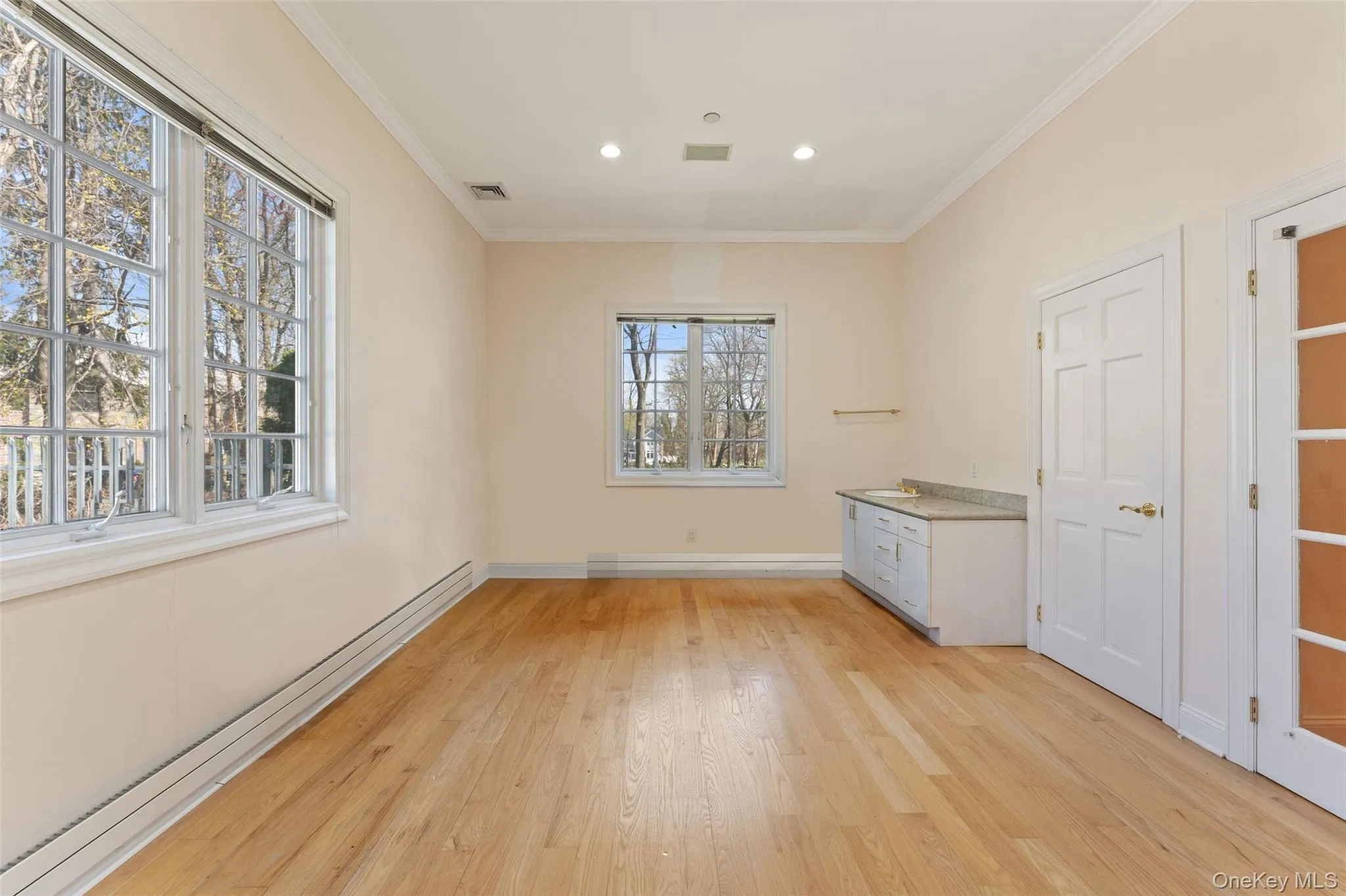 1st floor bedroom with baseboard heating, light wood finished floors, crown molding, and recessed lighting 1st floor bedroom with baseboard heating, light wood finished floors, crown molding, and recessed lighting