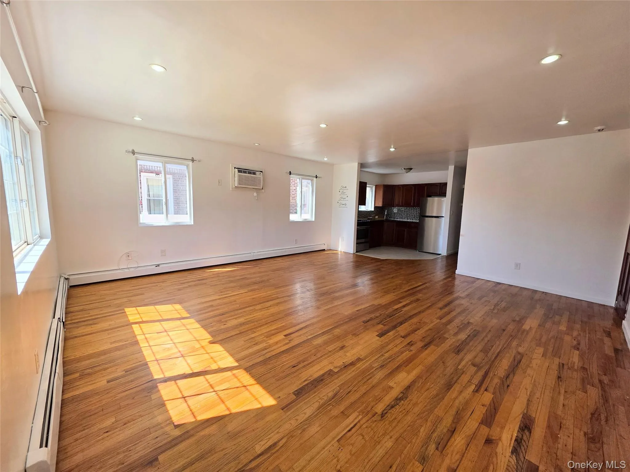 Unfurnished living room with dark wood-style floors, baseboard heating, and recessed lighting Unfurnished living room with dark wood-style floors, baseboard heating, and recessed lighting
