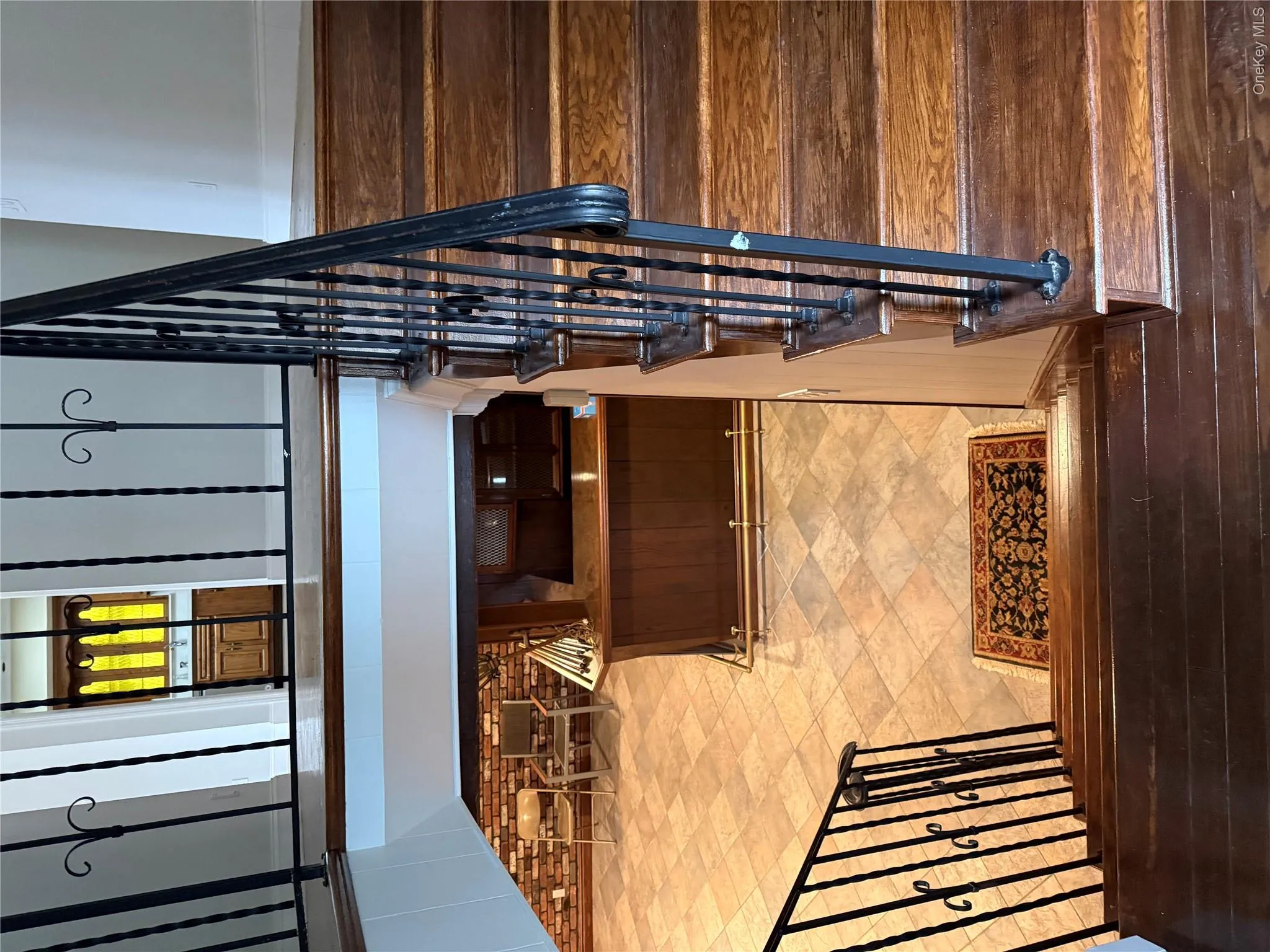 The property features hardwood stairs with ornate wrought iron railings, leading down to a tiled floor area The property features hardwood stairs with ornate wrought iron railings, leading down to a tiled floor area