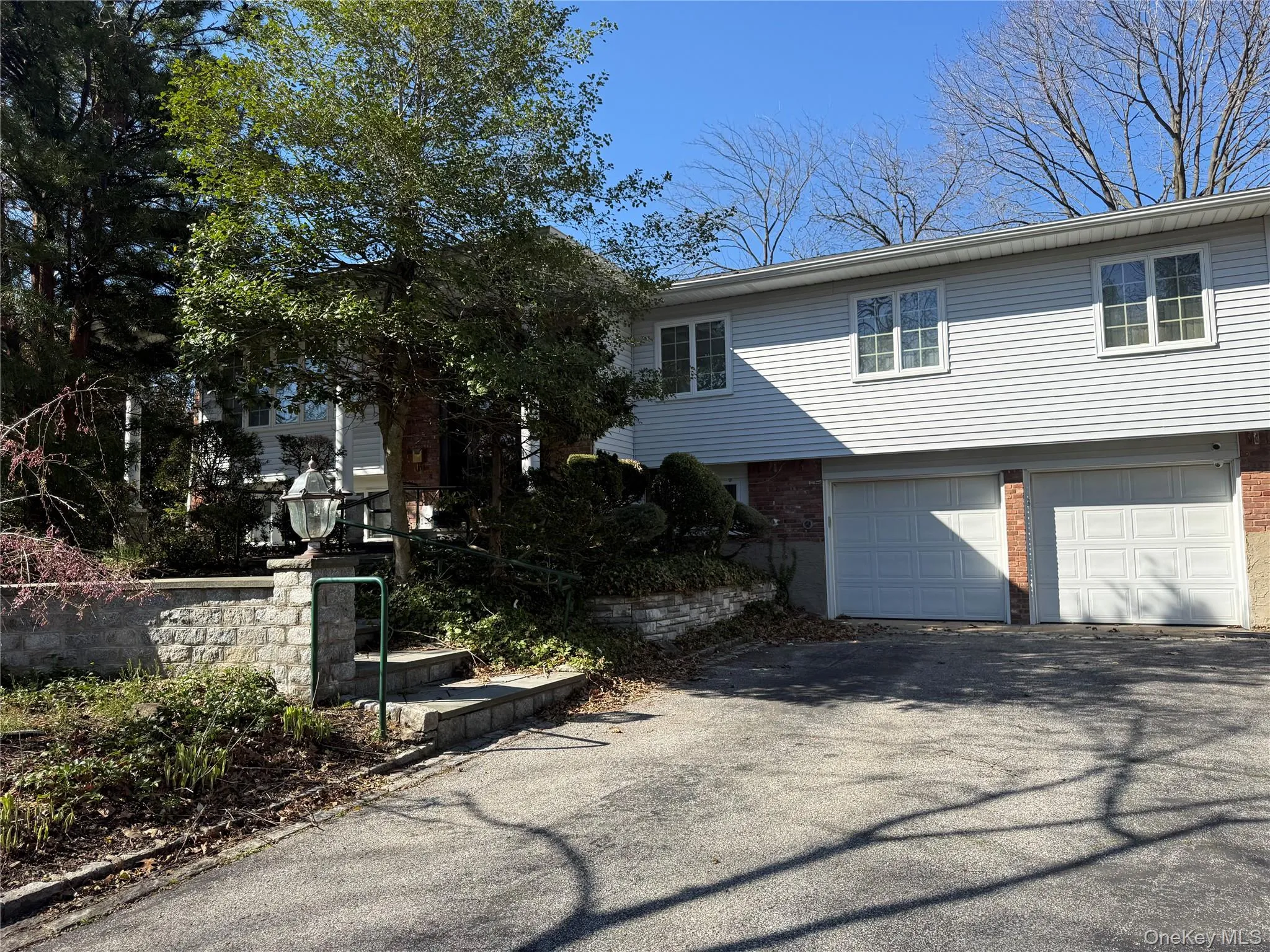 The property features white siding, a brick facade, and two garage doors The property features white siding, a brick facade, and two garage doors
