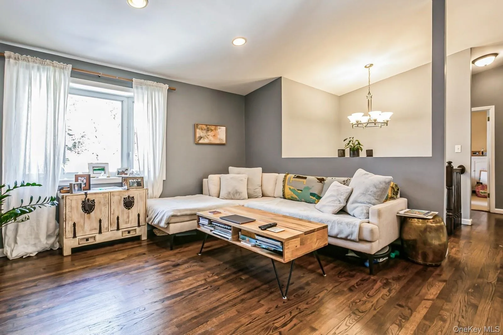 Living room featuring vaulted ceiling, dark wood-type flooring, recessed lighting, and an inviting chandelier Living room featuring vaulted ceiling, dark wood-type flooring, recessed lighting, and an inviting chandelier