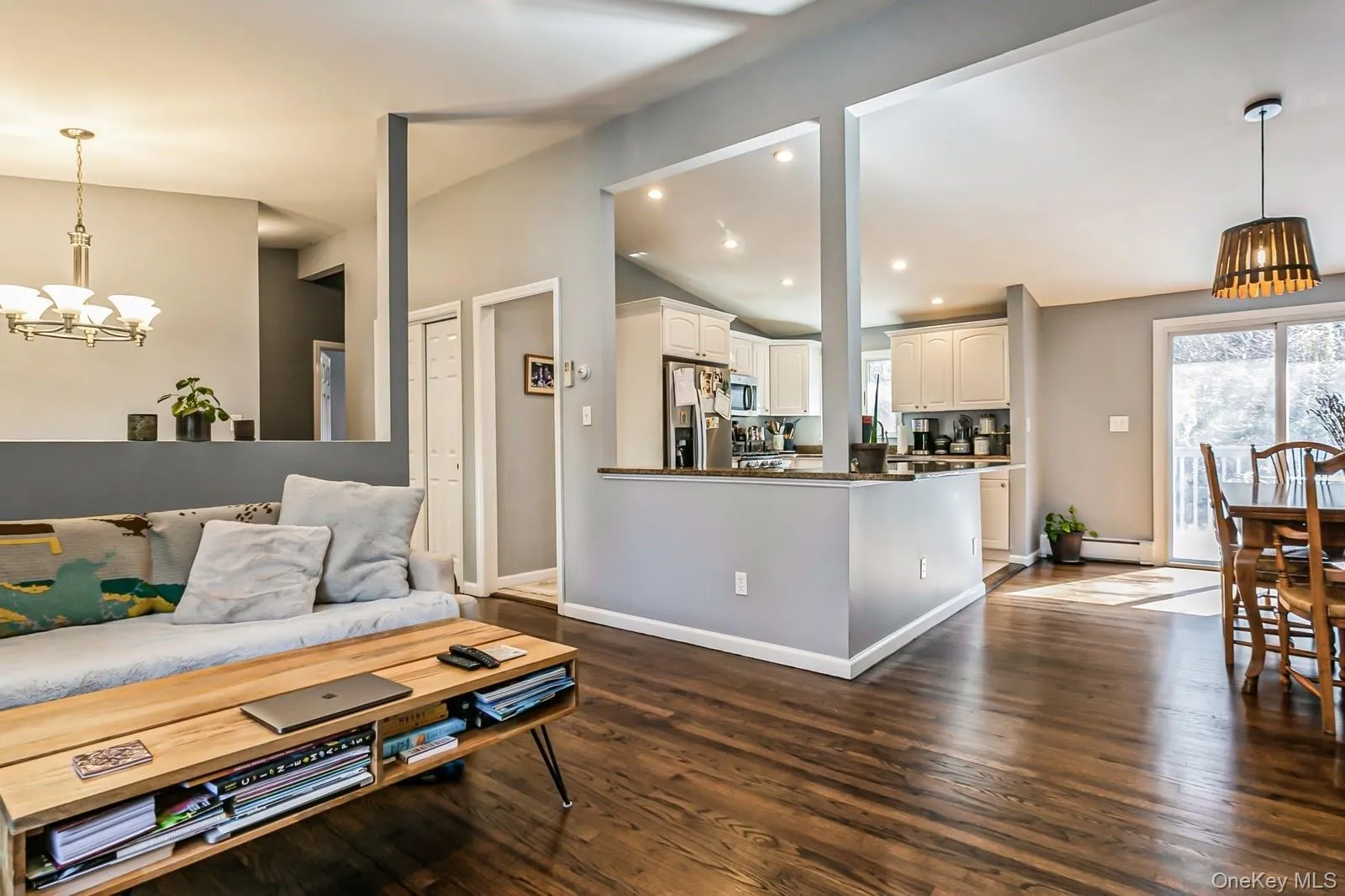 Living area featuring a wealth of natural light, lofted ceiling, dark wood-style flooring, and a baseboard radiator Living area featuring a wealth of natural light, lofted ceiling, dark wood-style flooring, and a baseboard radiator