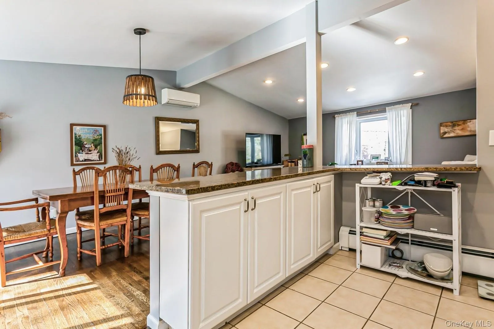 Kitchen featuring lofted ceiling with beams, hanging light fixtures, a wall mounted AC, white cabinetry, and light tile patterned flooring Kitchen featuring lofted ceiling with beams, hanging light fixtures, a wall mounted AC, white cabinetry, and light tile patterned flooring