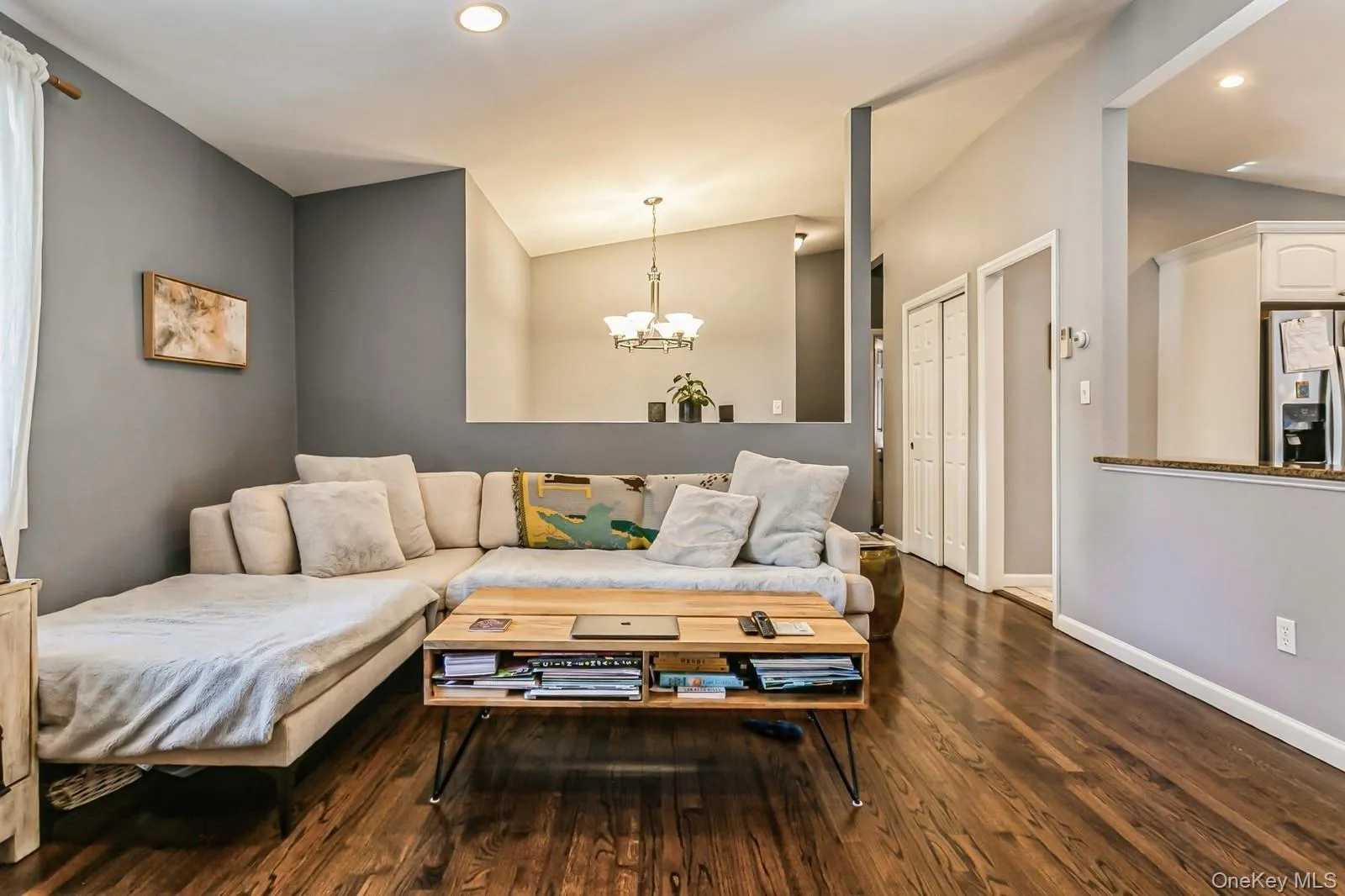 Living area featuring dark wood-type flooring, recessed lighting, a chandelier, and baseboards Living area featuring dark wood-type flooring, recessed lighting, a chandelier, and baseboards