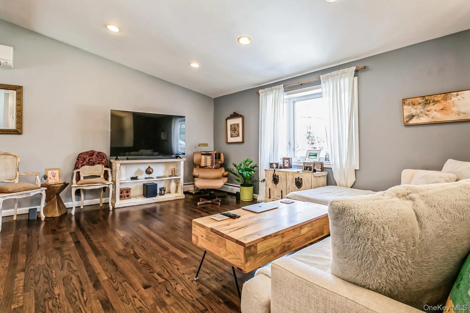 Living area with lofted ceiling, a wall unit AC, wood finished floors, a baseboard heating unit, and recessed lighting Living area with lofted ceiling, a wall unit AC, wood finished floors, a baseboard heating unit, and recessed lighting