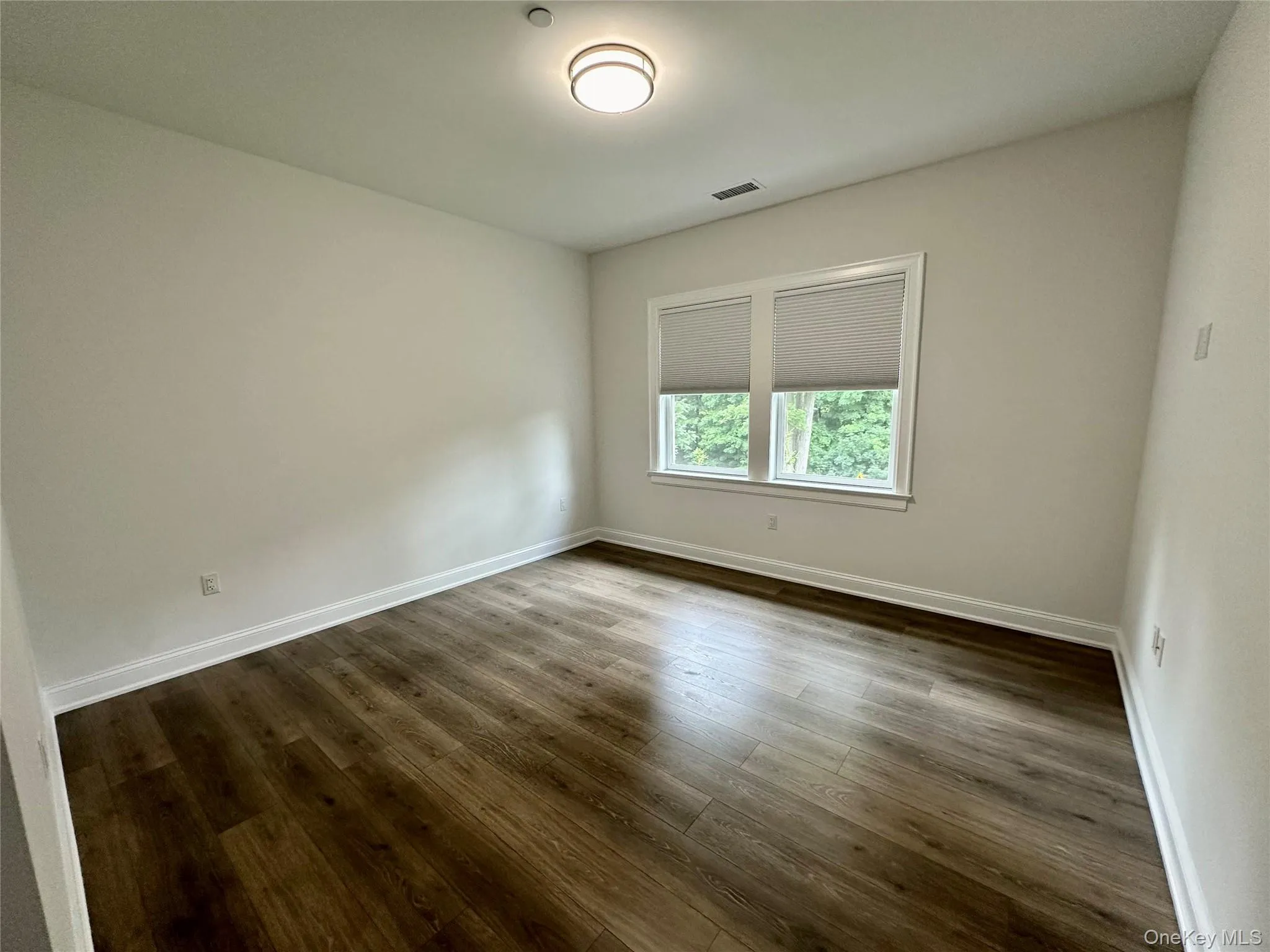 Empty room featuring dark wood finished floors and baseboards Empty room featuring dark wood finished floors and baseboards