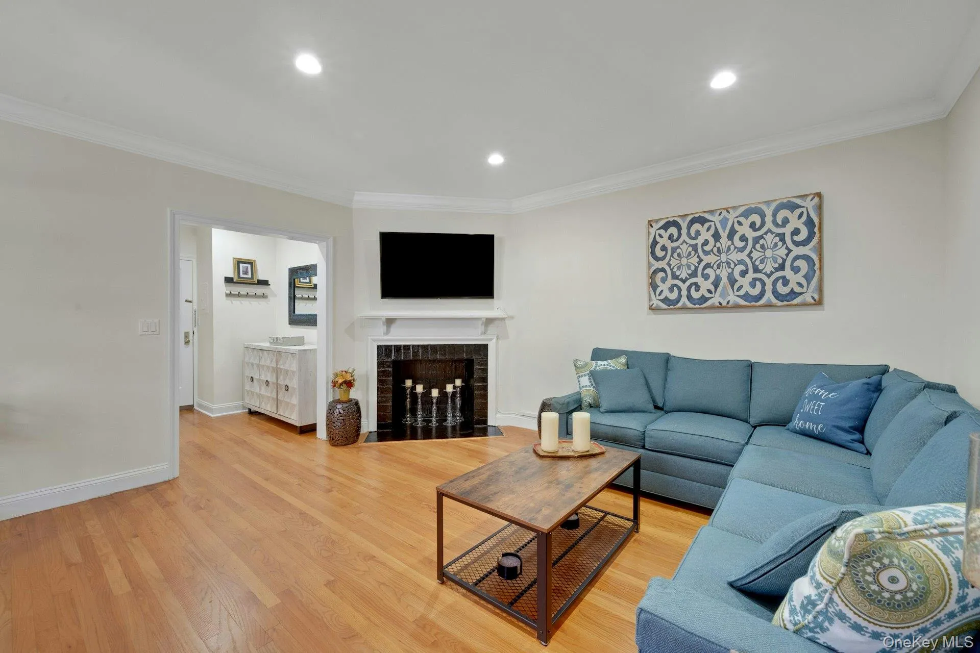 Living area with crown molding, wood finished floors, recessed lighting, and a fireplace with flush hearth Living area with crown molding, wood finished floors, recessed lighting, and a fireplace with flush hearth
